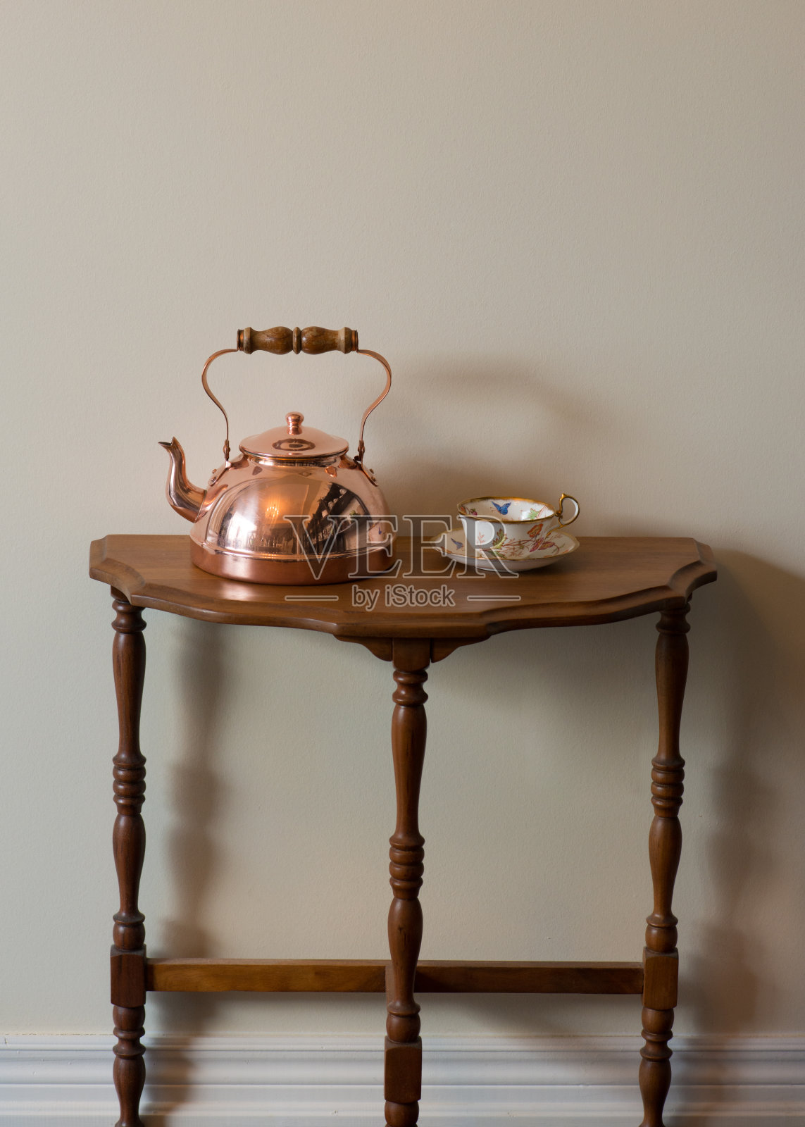 傍晚阳光下胡桃木边桌上的古董铜茶壶和古董英式茶杯照片摄影图片