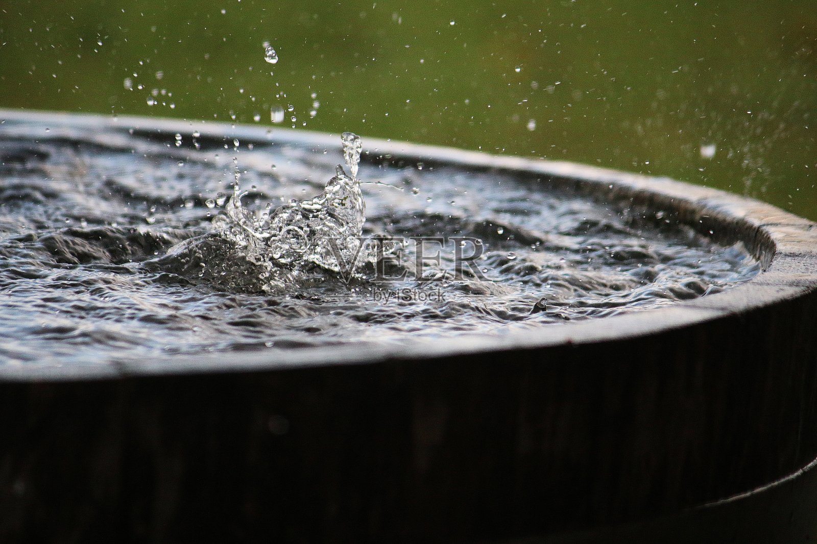 雨水落在花园里一个装满水的木桶里照片摄影图片