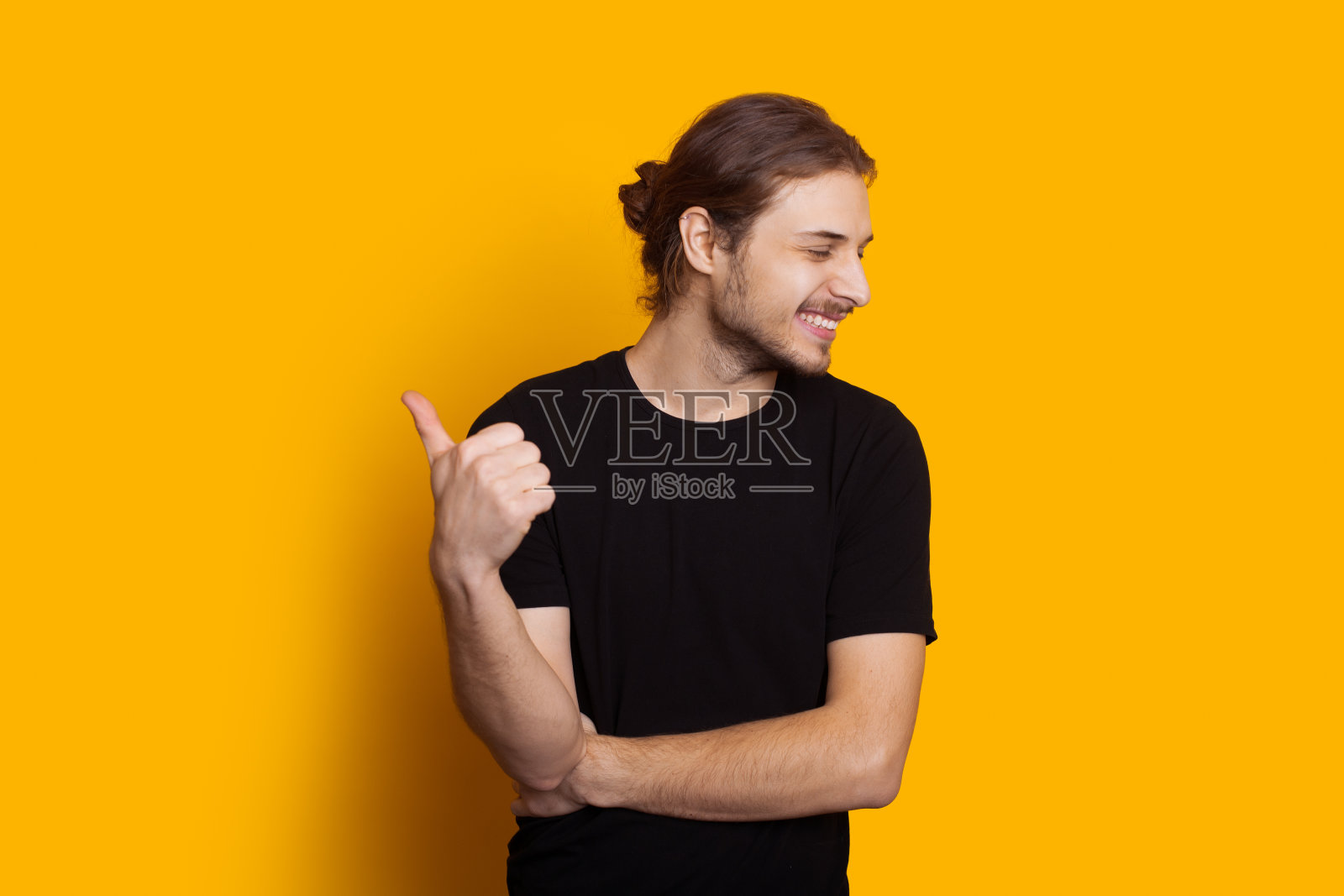 一名留着长胡子的黑人白人男子在黄色背景下微笑着指着天空照片摄影图片