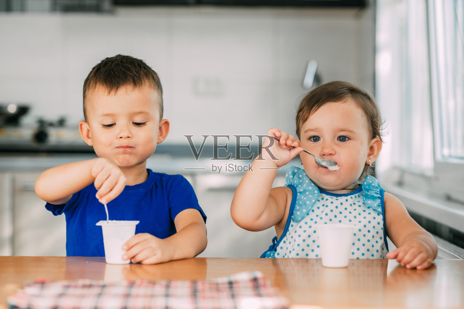 一个温暖的夏日，男孩和女孩在厨房里吃酸奶照片摄影图片