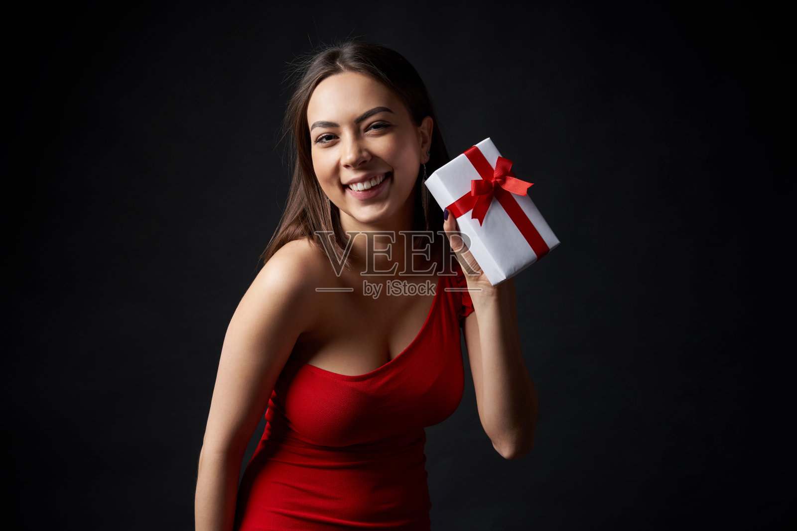 穿着红色晚礼服的漂亮女人拿着礼盒照片摄影图片