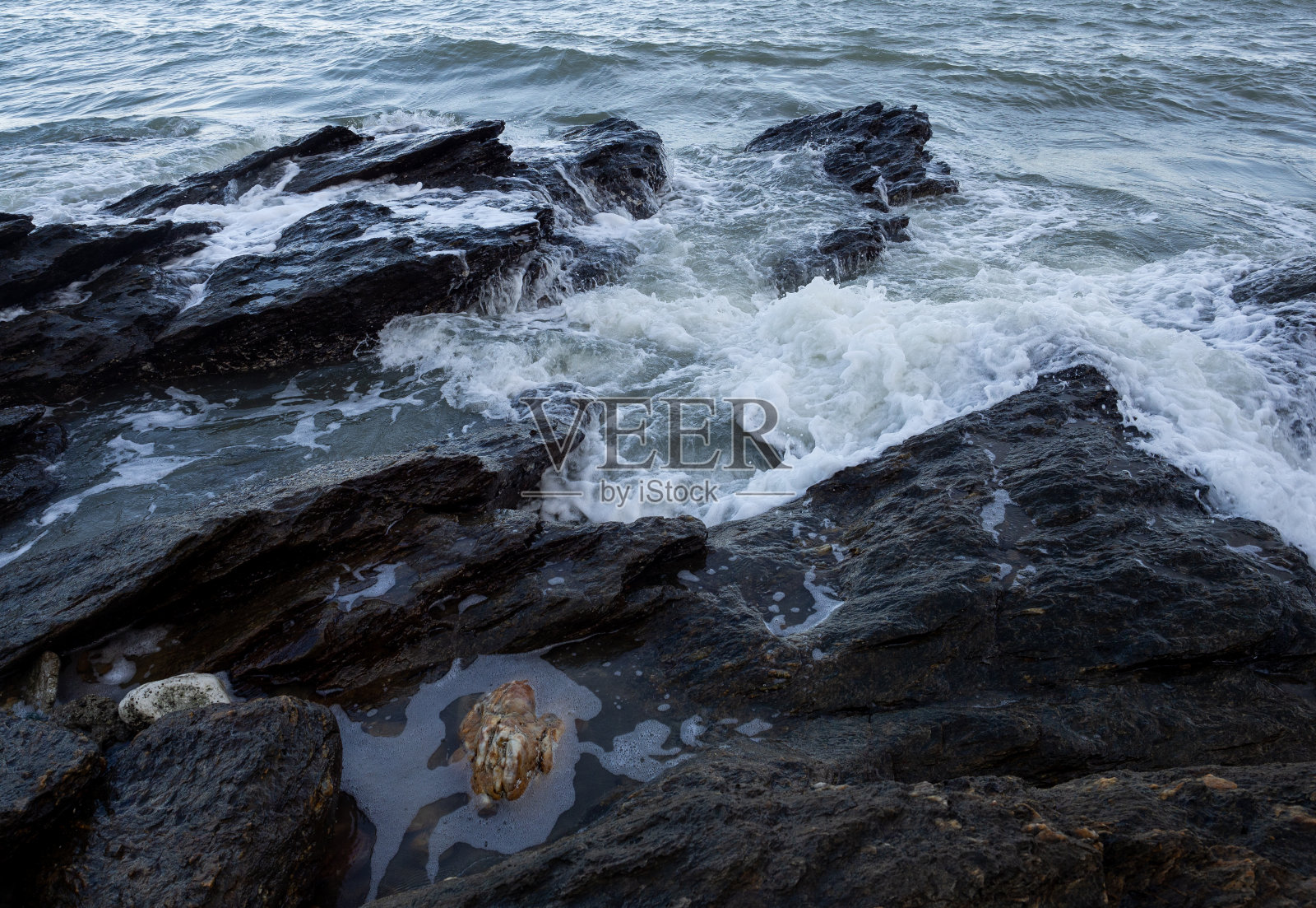 海浪涌向多岩石的海岸。照片摄影图片