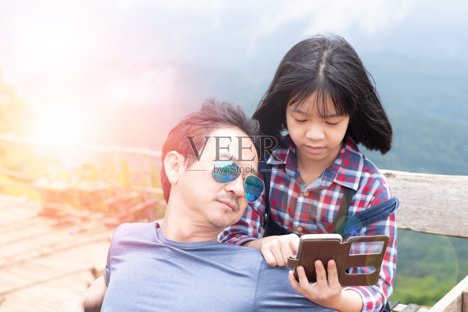 幸福家庭，科技理念。父亲和女儿的孩子在假期旅行中一起用智能手机查看位置。爸爸和女儿在自拍后用手机。照片摄影图片