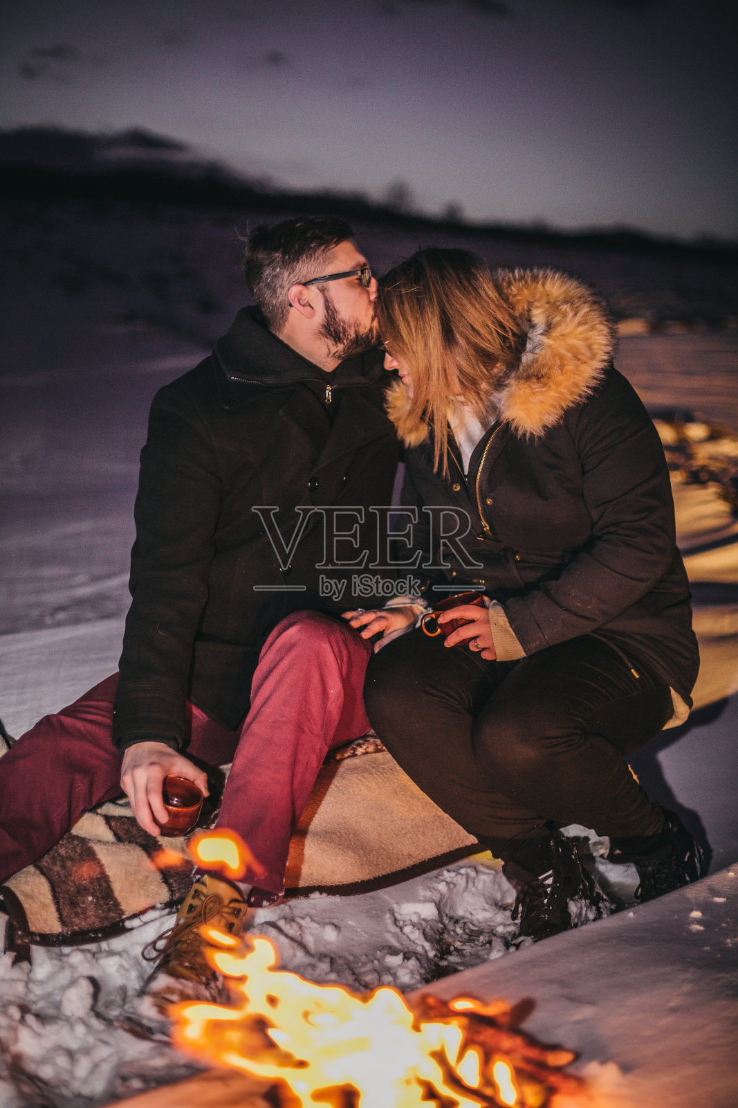 年轻夫妇在享受雪和火照片摄影图片