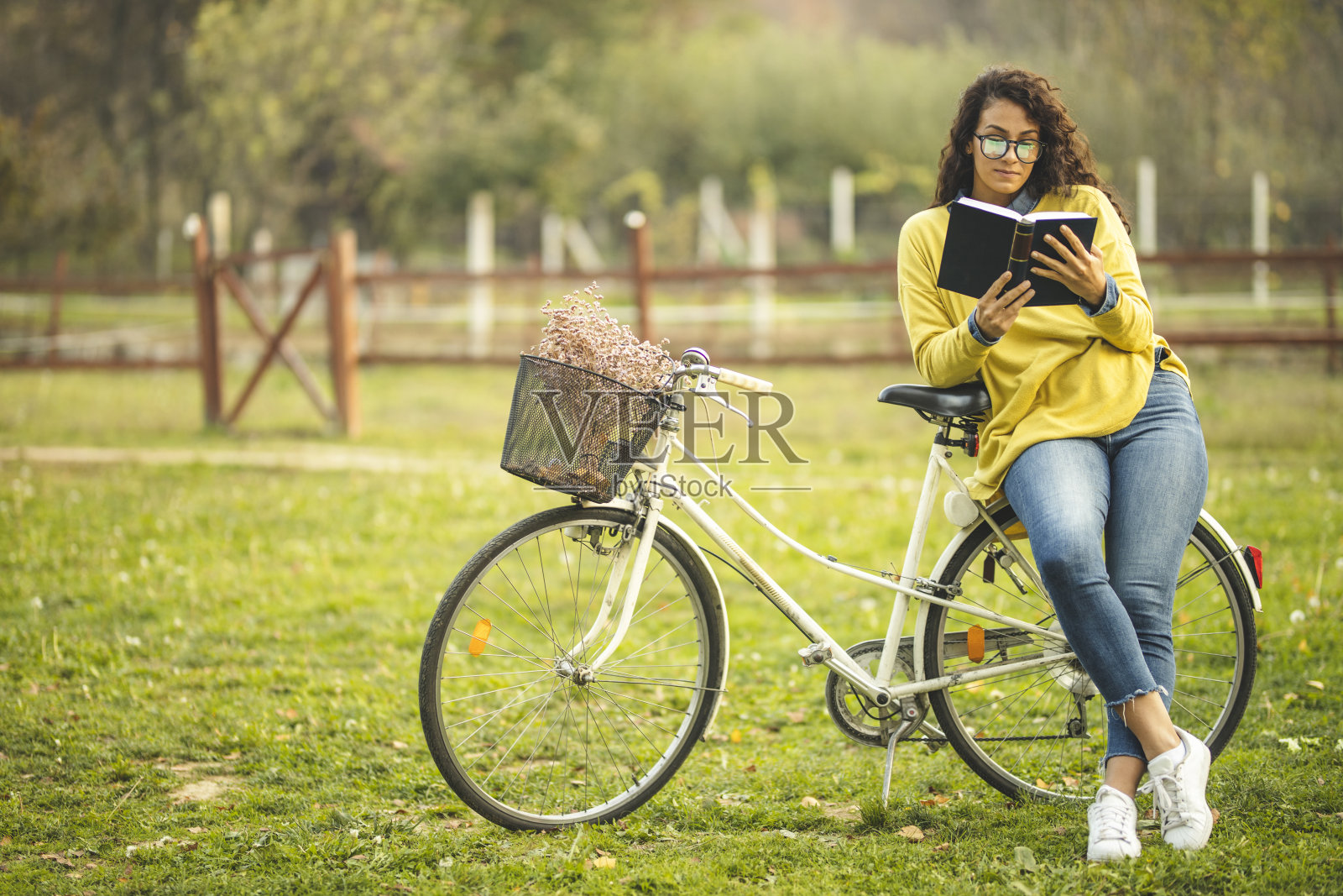 女人坐在自行车上看书照片摄影图片