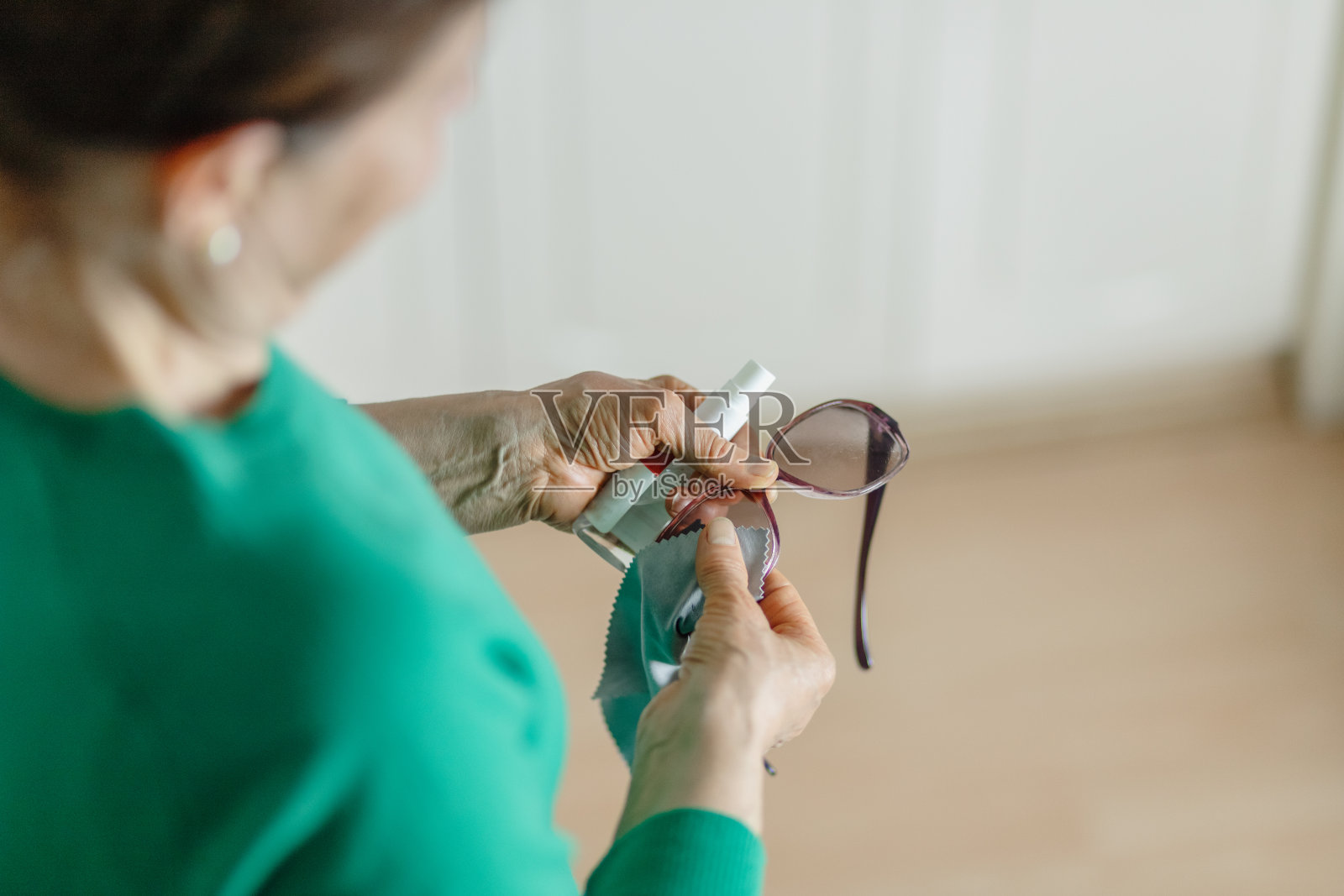 成熟的女人用消毒剂清洁她的眼镜照片摄影图片