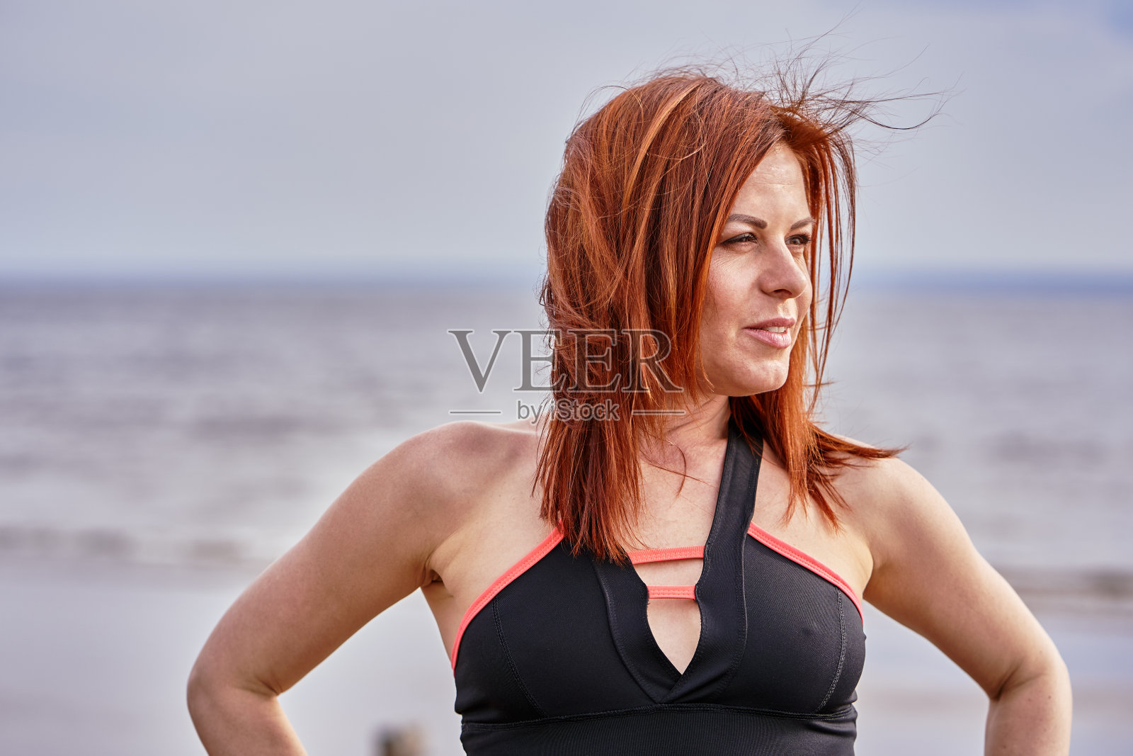一个红头发的中年妇女沿着河岸走的肖像。阳光明媚的春天的早晨。特写镜头。照片摄影图片