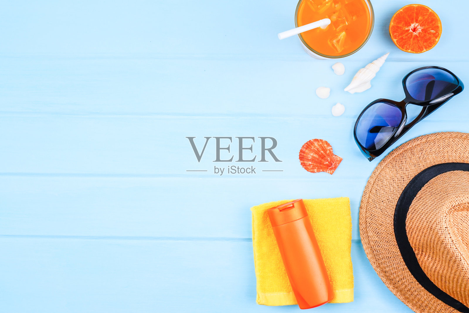 顶视图旅游背景概念太阳镜，橙汁，沙滩帽和配件在蓝色木材背景。照片摄影图片