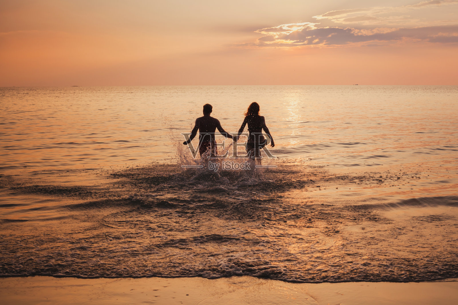 日落时分，海滩上一对情侣的剪影，祝两人节日快乐照片摄影图片