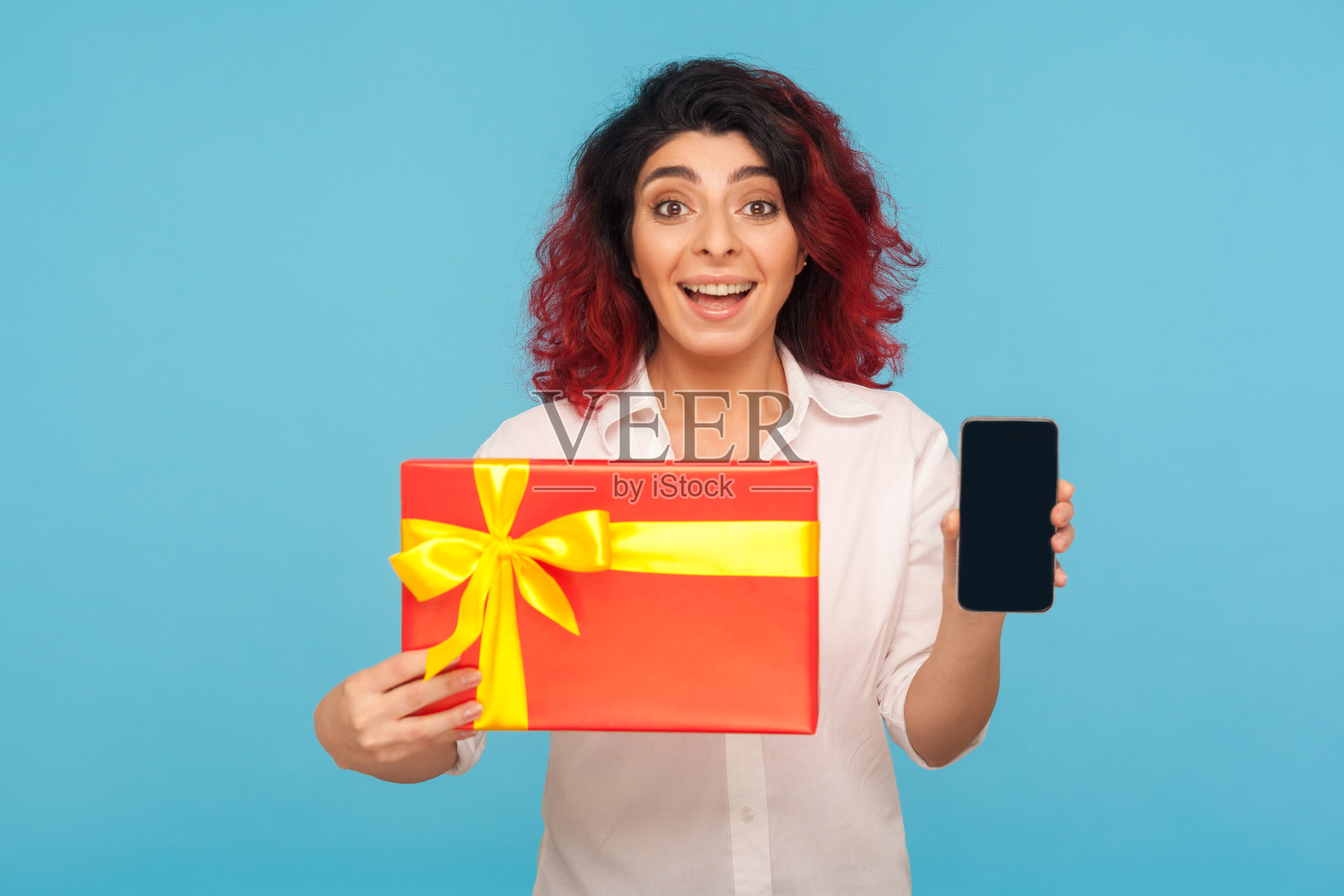 网上订单服务。一幅惊奇的红发女孩的肖像，展示了包装好的礼品盒和手机照片摄影图片