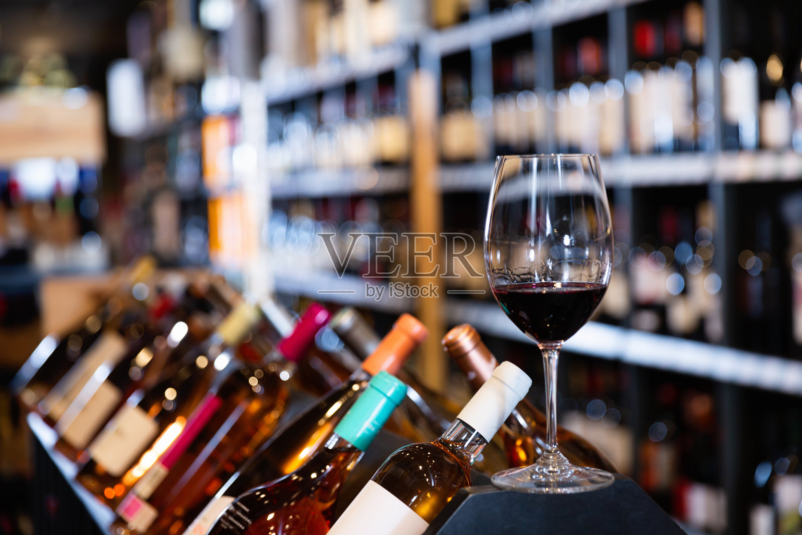 红酒酒杯的特写在模糊的背景与货架上的葡萄酒商店照片摄影图片