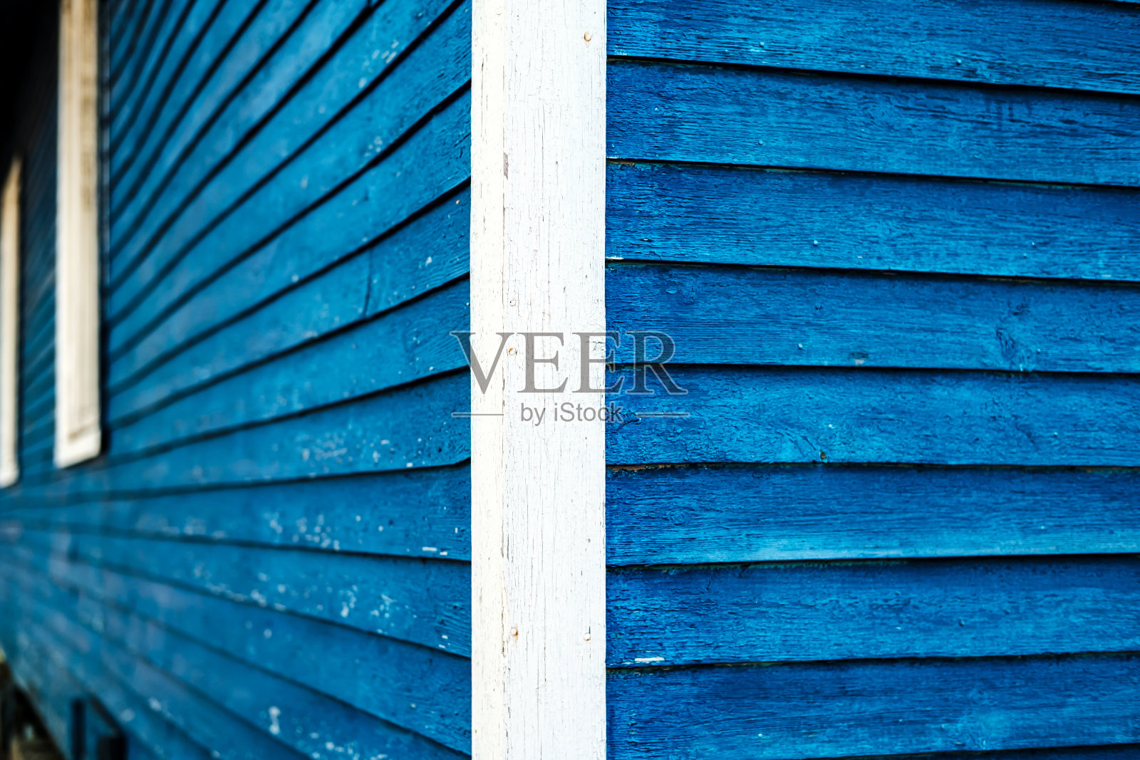 木屋的一角，镶着木板，漆着亮蓝色和白色。照片摄影图片