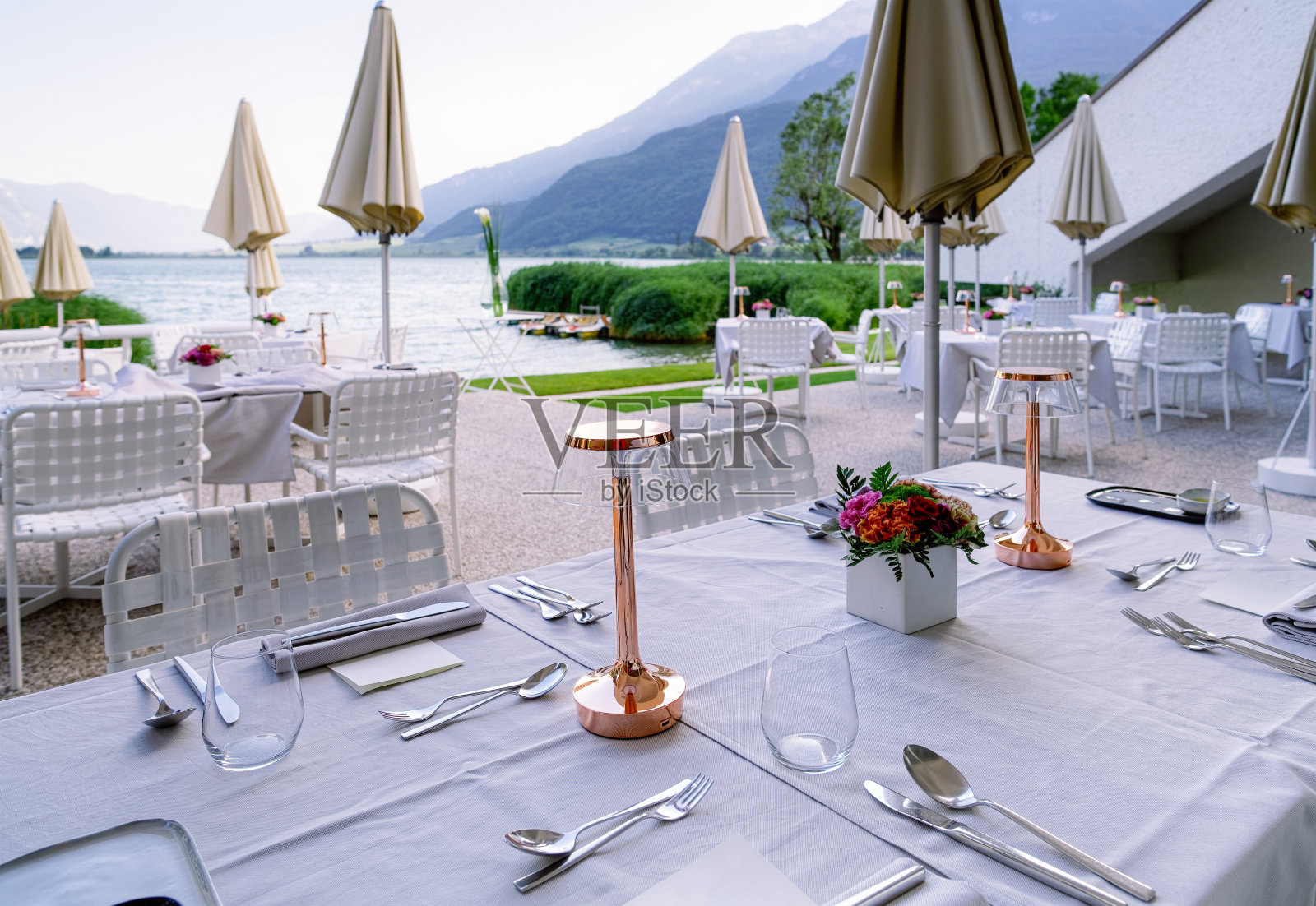 意大利卡尔达罗湖畔的豪华街头餐厅，白色桌布和鲜花照片摄影图片