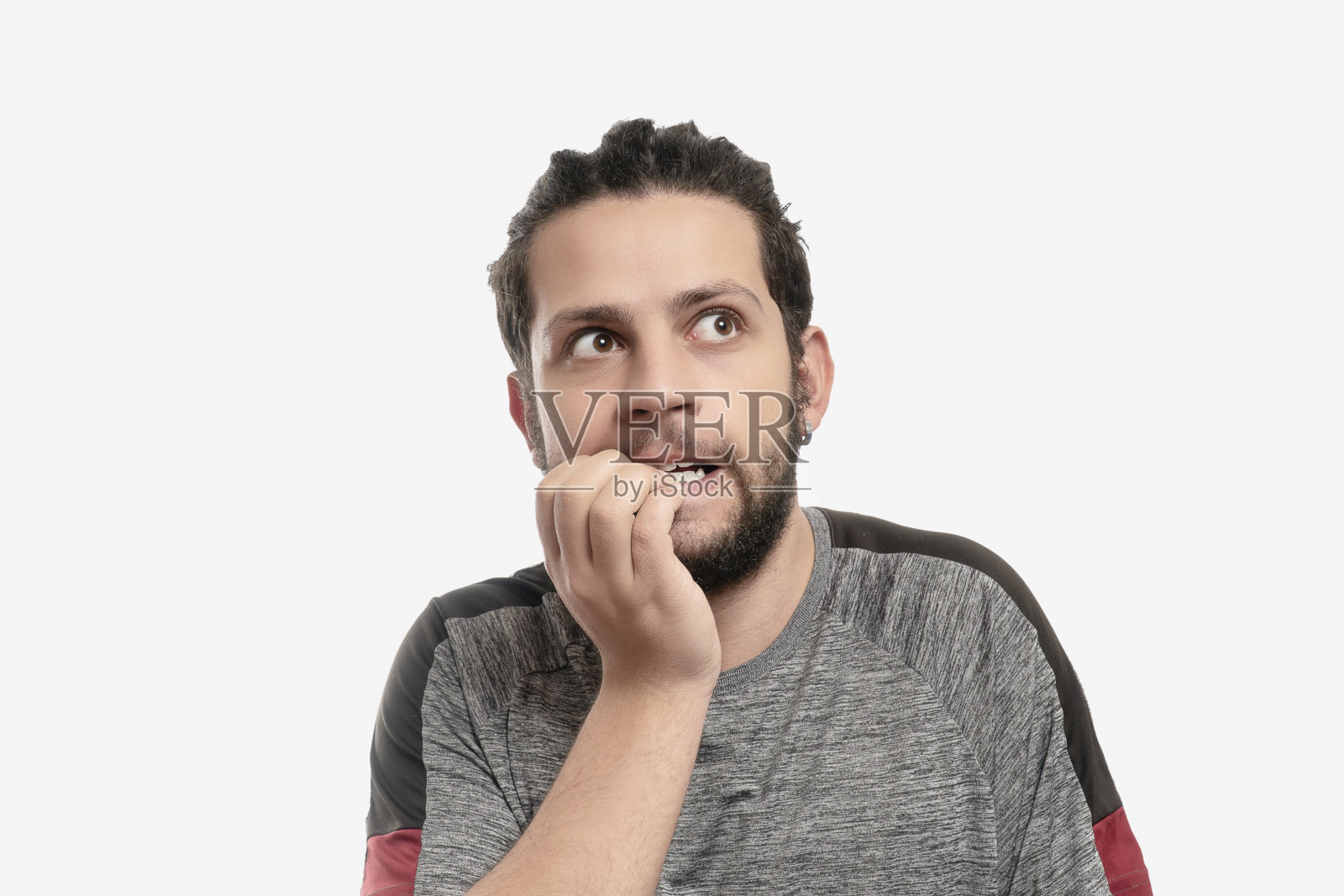 一幅焦虑的年轻人在灰色背景下咬指甲的肖像照片摄影图片
