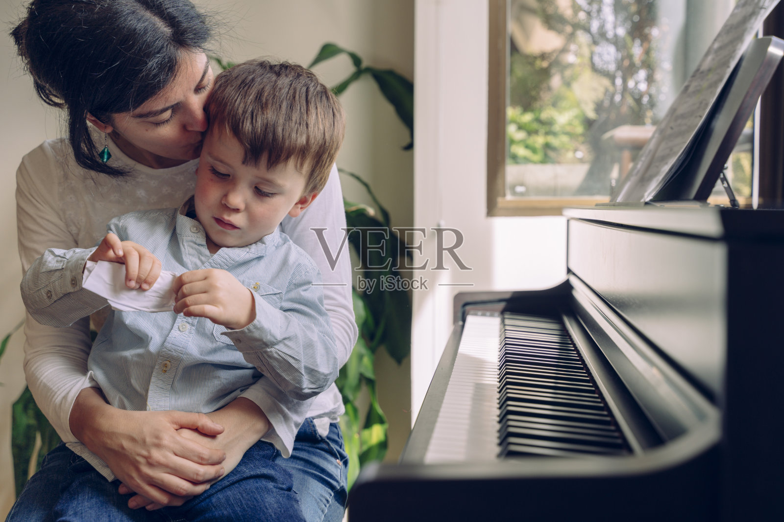 妈妈在家里教儿子钢琴课。照片摄影图片