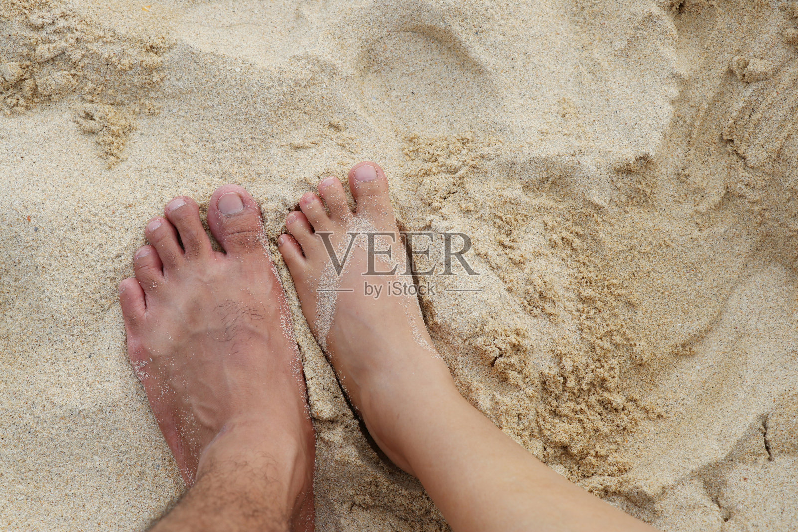 女人和男人的脚踩在沙滩上的沙子上。照片摄影图片