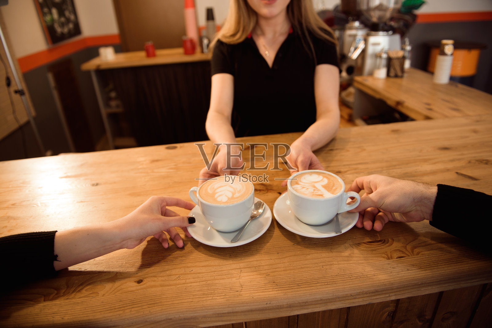 友好的调酒师在现代咖啡店的内部为顾客提供意式浓缩咖啡。照片摄影图片