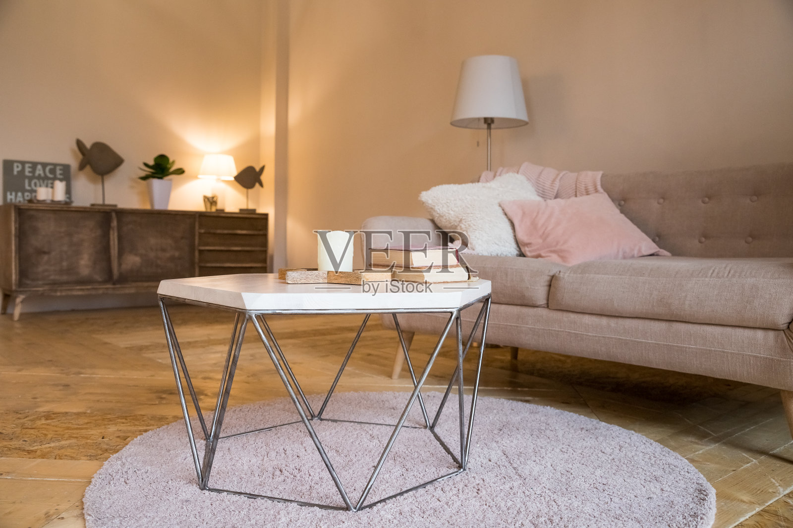 小咖啡桌和蜡烛旁边设计的沙发和彩色枕头。北欧客厅的静物细节。明亮的客厅内部。客厅里优雅的沙发照片摄影图片