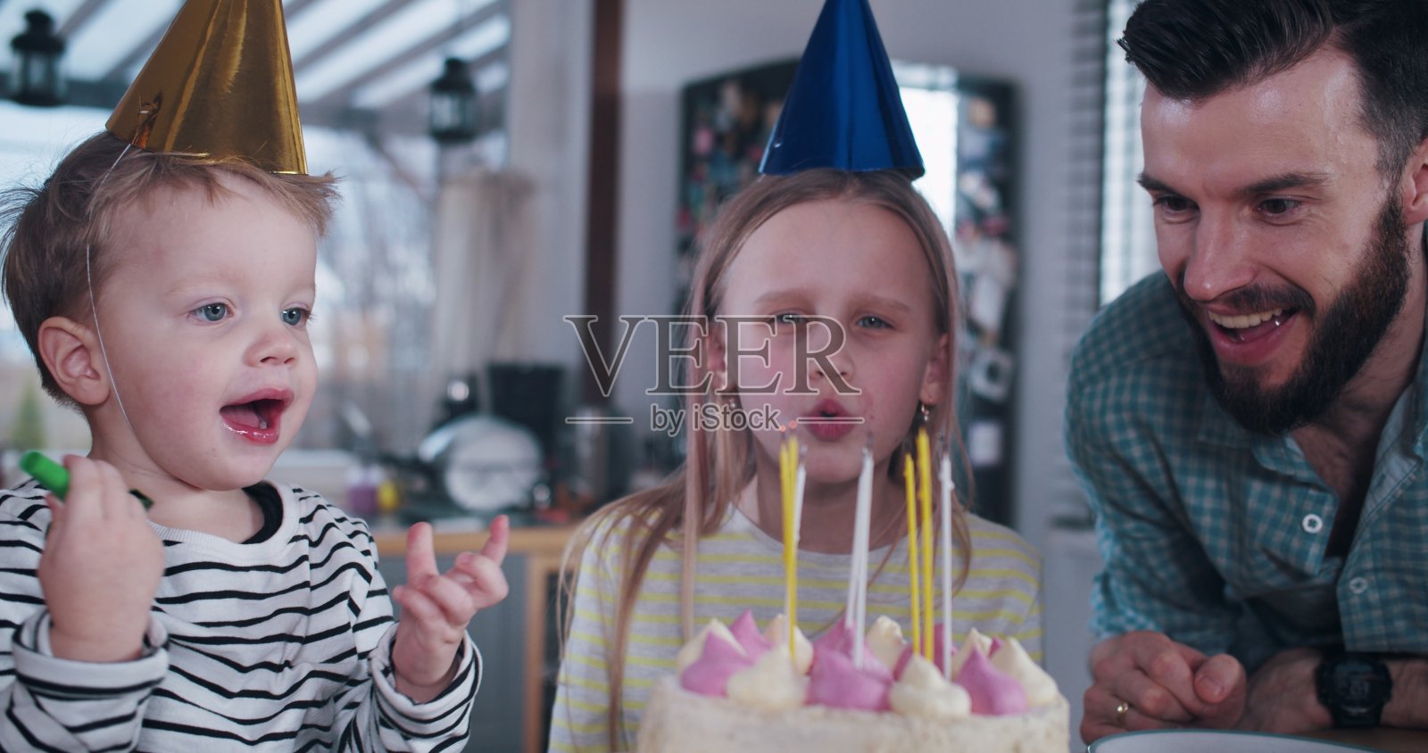 快乐的年轻欧洲少女孩子吹生日蛋糕，庆祝派对在家里与家人的慢镜头。照片摄影图片