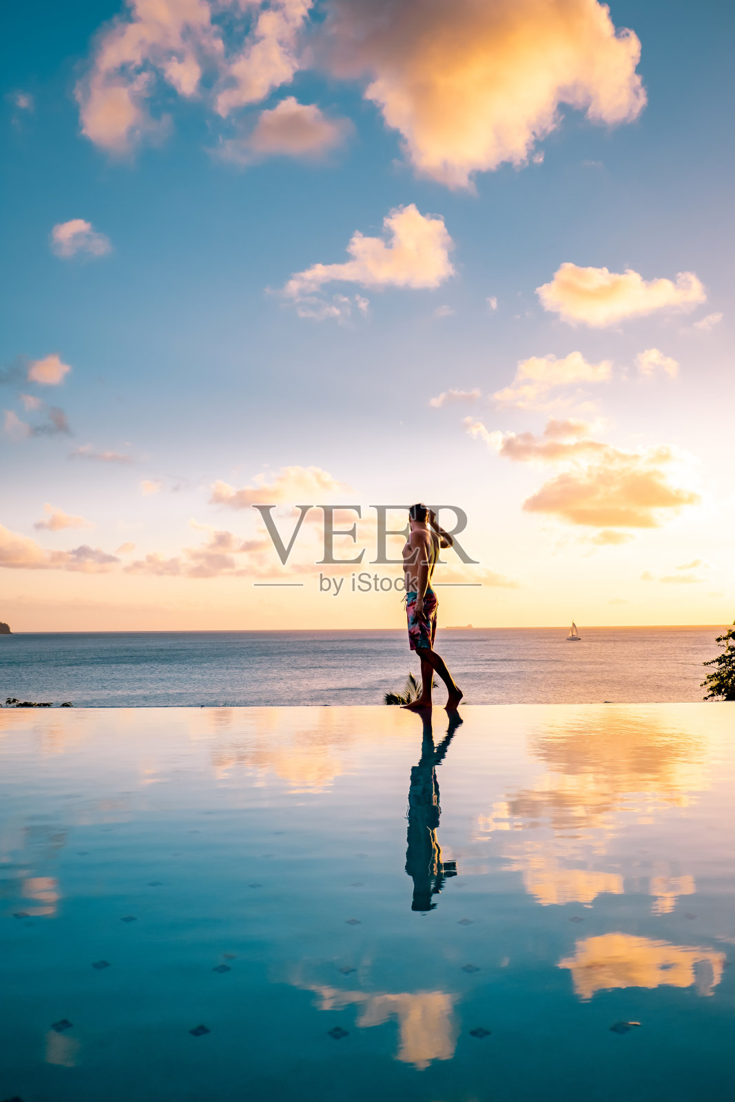 加勒比圣卢西亚岛，小伙子在游泳池边看日落，男子在圣卢西亚的游泳池里照片摄影图片