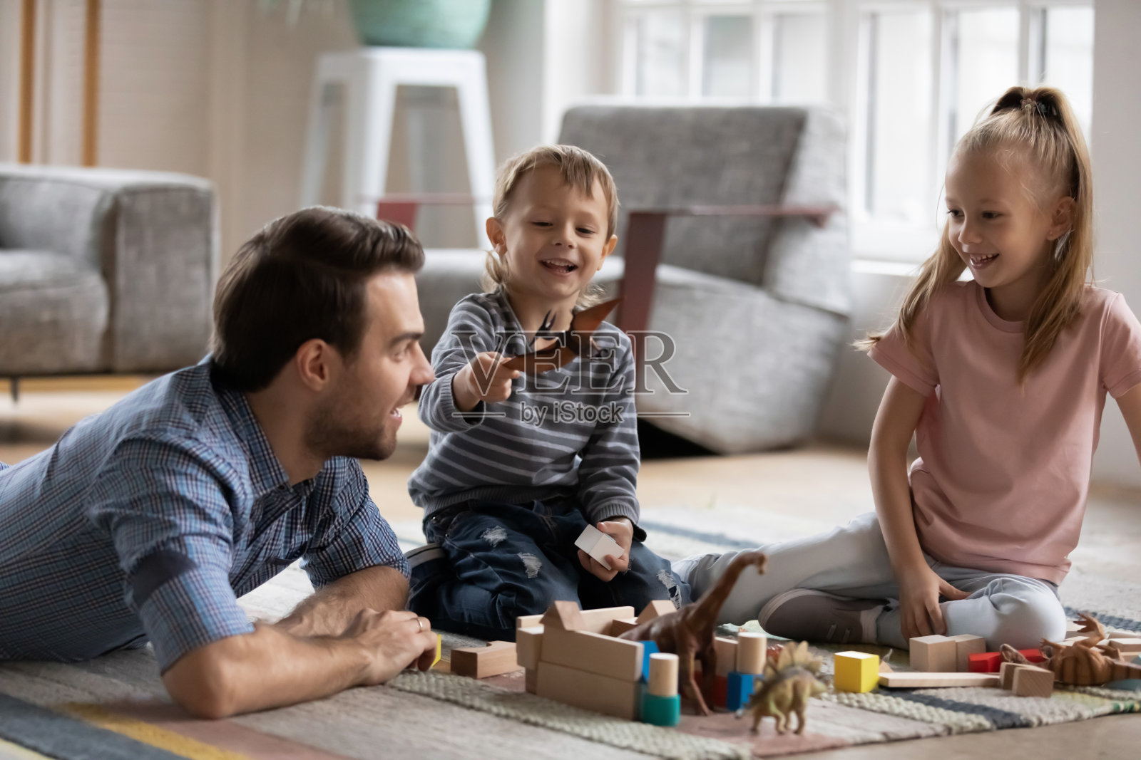 快乐的小男孩与爸爸和姐姐在家里玩得开心。照片摄影图片