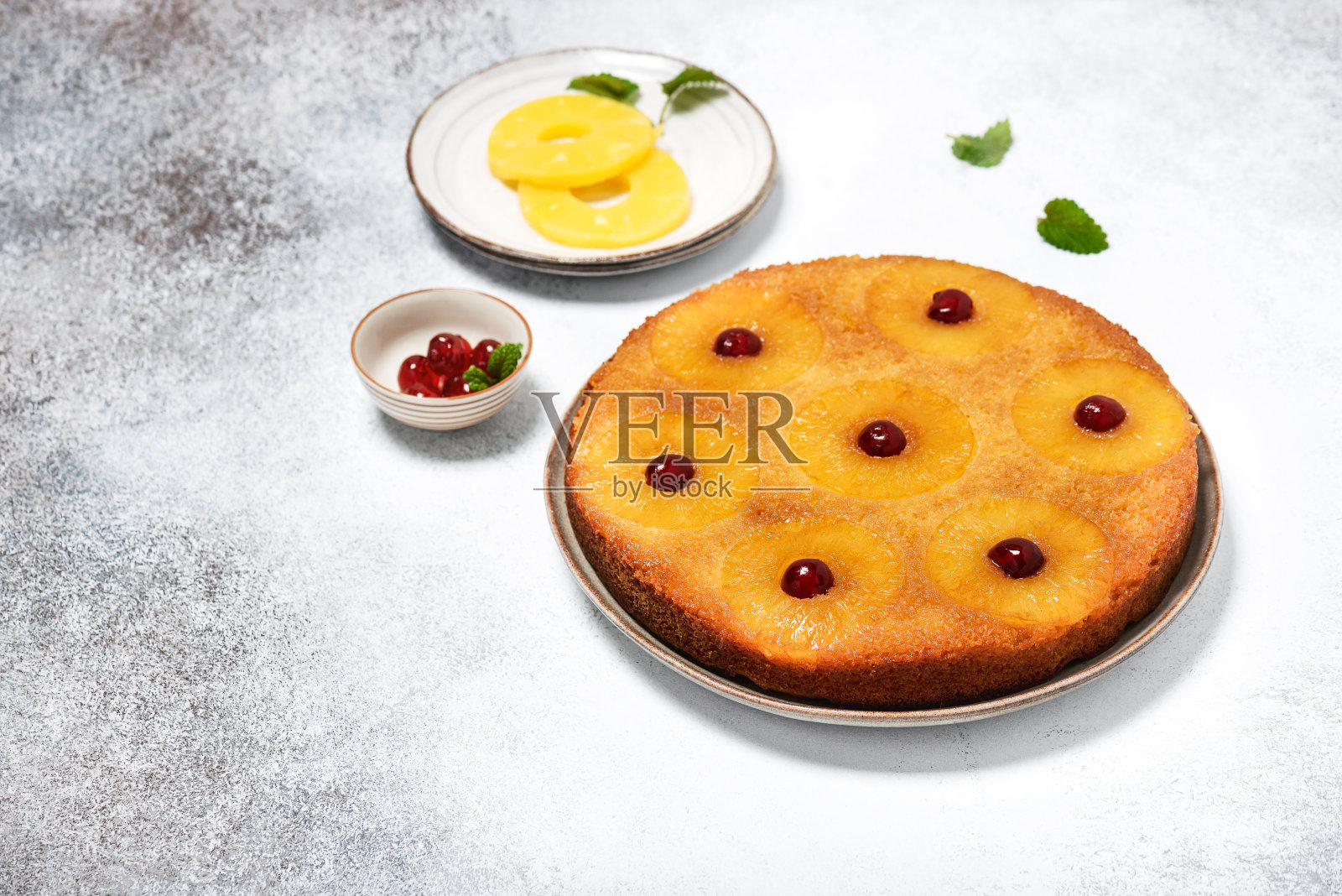 传统的新鲜烤菠萝颠倒蛋糕与糖霜樱桃在一个轻乡村背景。照片摄影图片