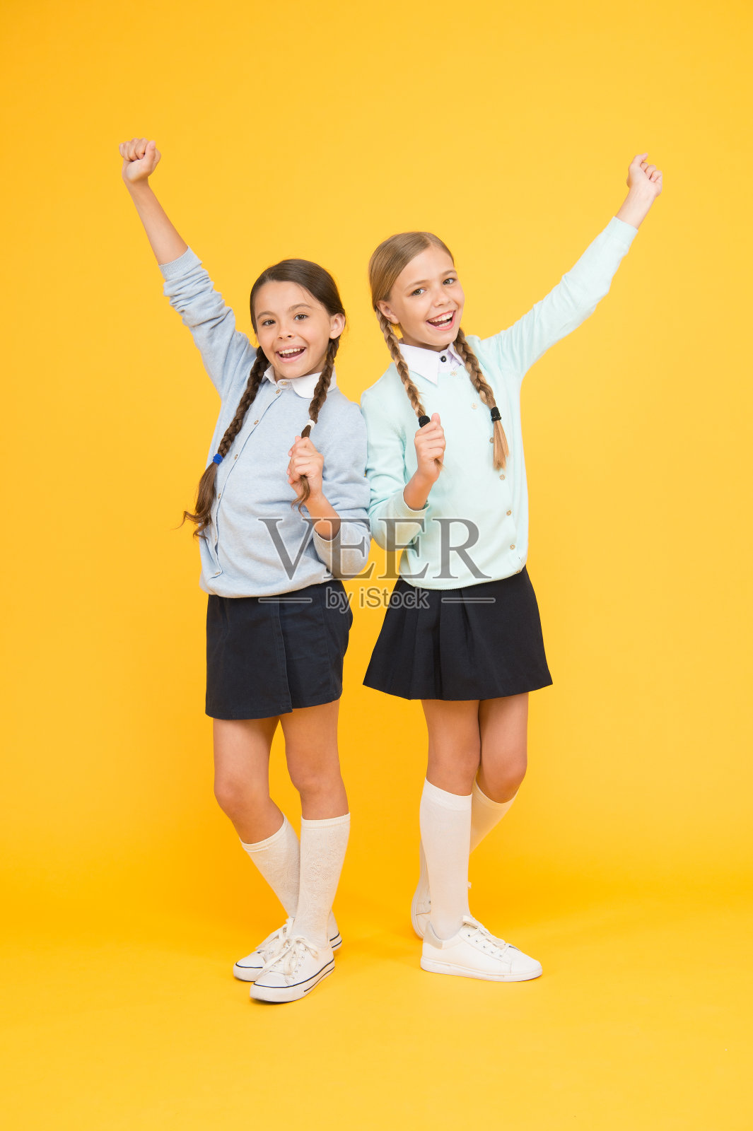 穿着校服的快乐女孩。黄色背景下聪明的小女孩。教育的概念。回到学校。孩子的时尚。友谊和姐妹。知识的一天。童年的幸福。只是启发照片摄影图片