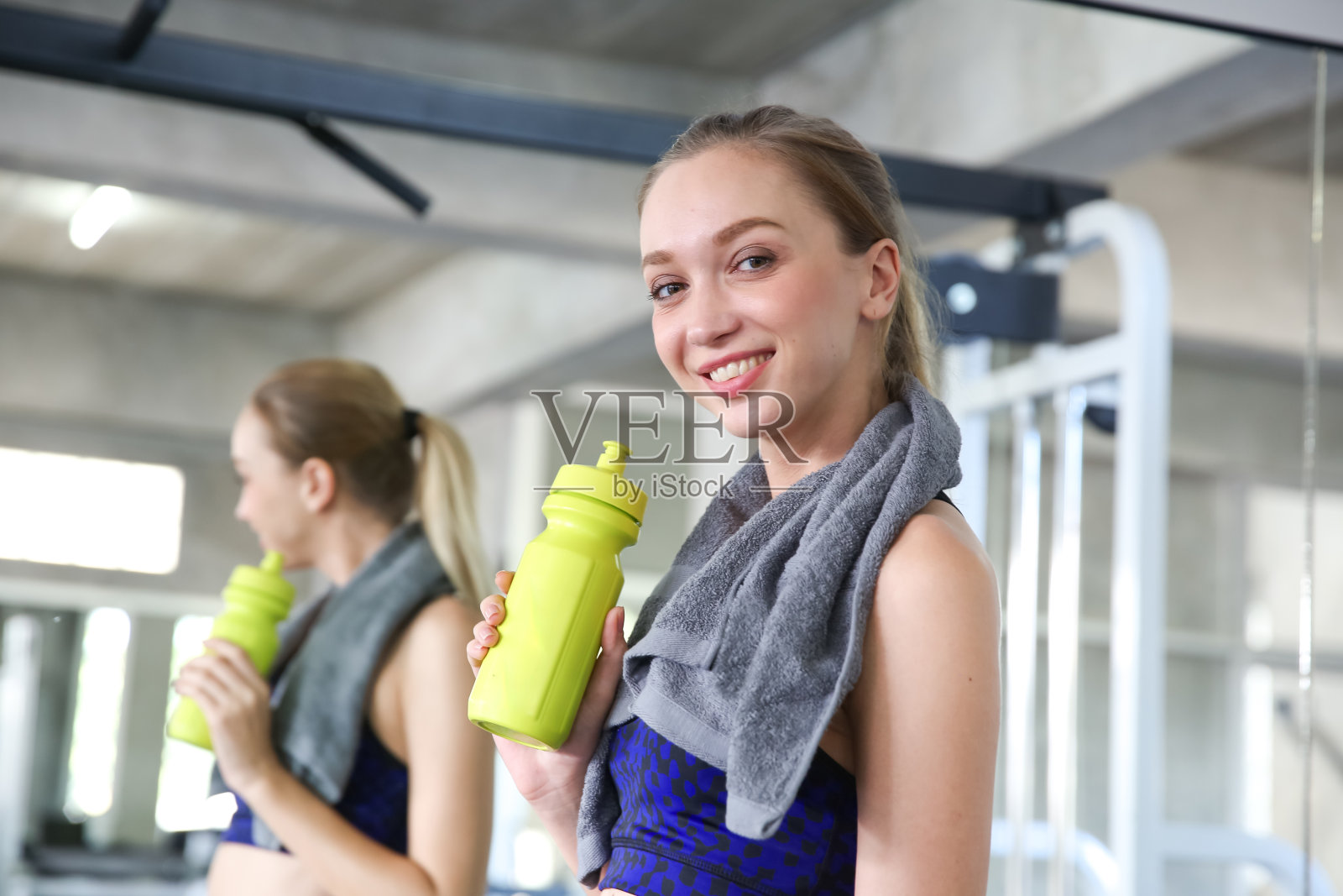 年轻的运动女性在健身房喝水。女性喝水。美丽年轻的白种女人在运动俱乐部健身后喝水。照片摄影图片