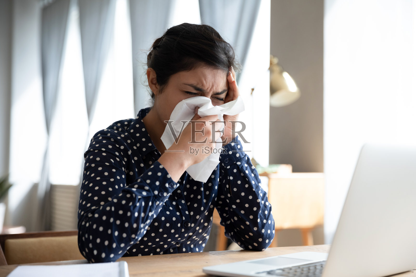 一个不健康的印度女人，在工作场所擤鼻涕照片摄影图片