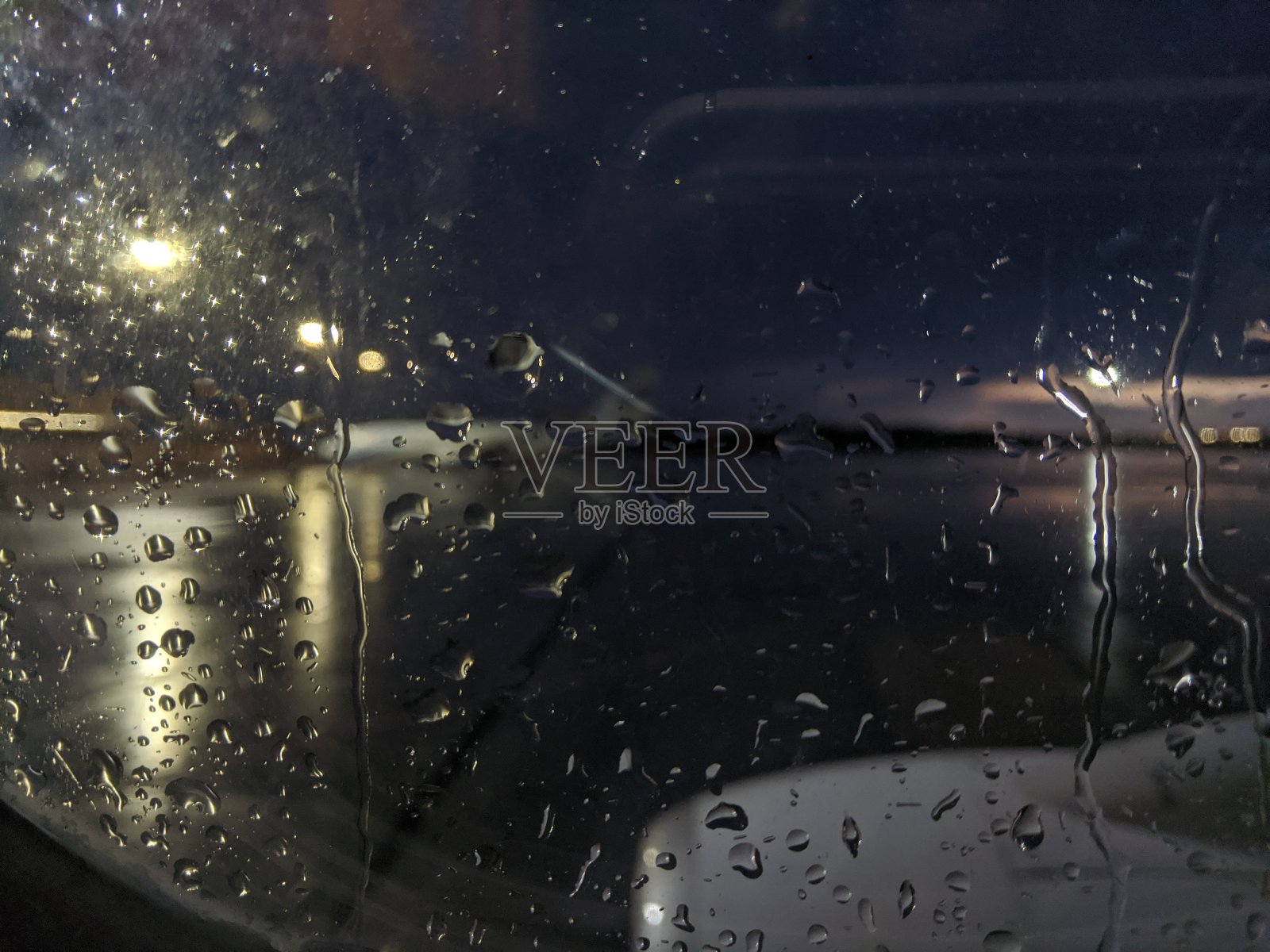 雨滴落在玻璃上。专注于滴药。夜晚的城市场景。飞机舷窗上的景色。照片摄影图片