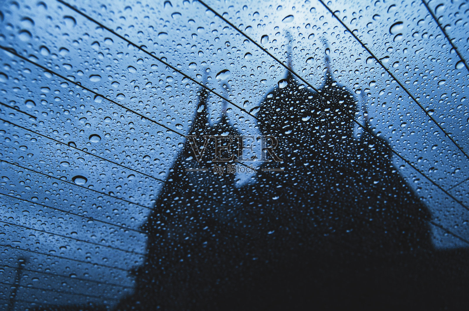 美丽的雨滴对汽车玻璃特写。背景是教堂的剪影照片摄影图片