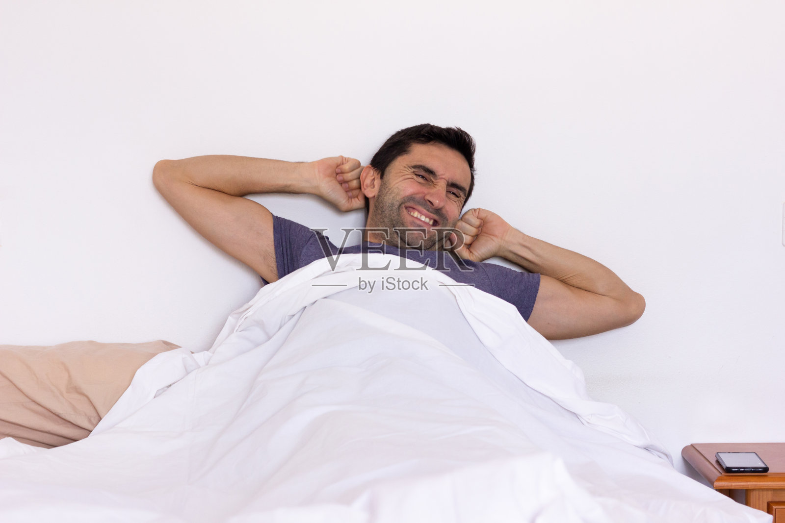 年轻人躺在白色床单下照片摄影图片
