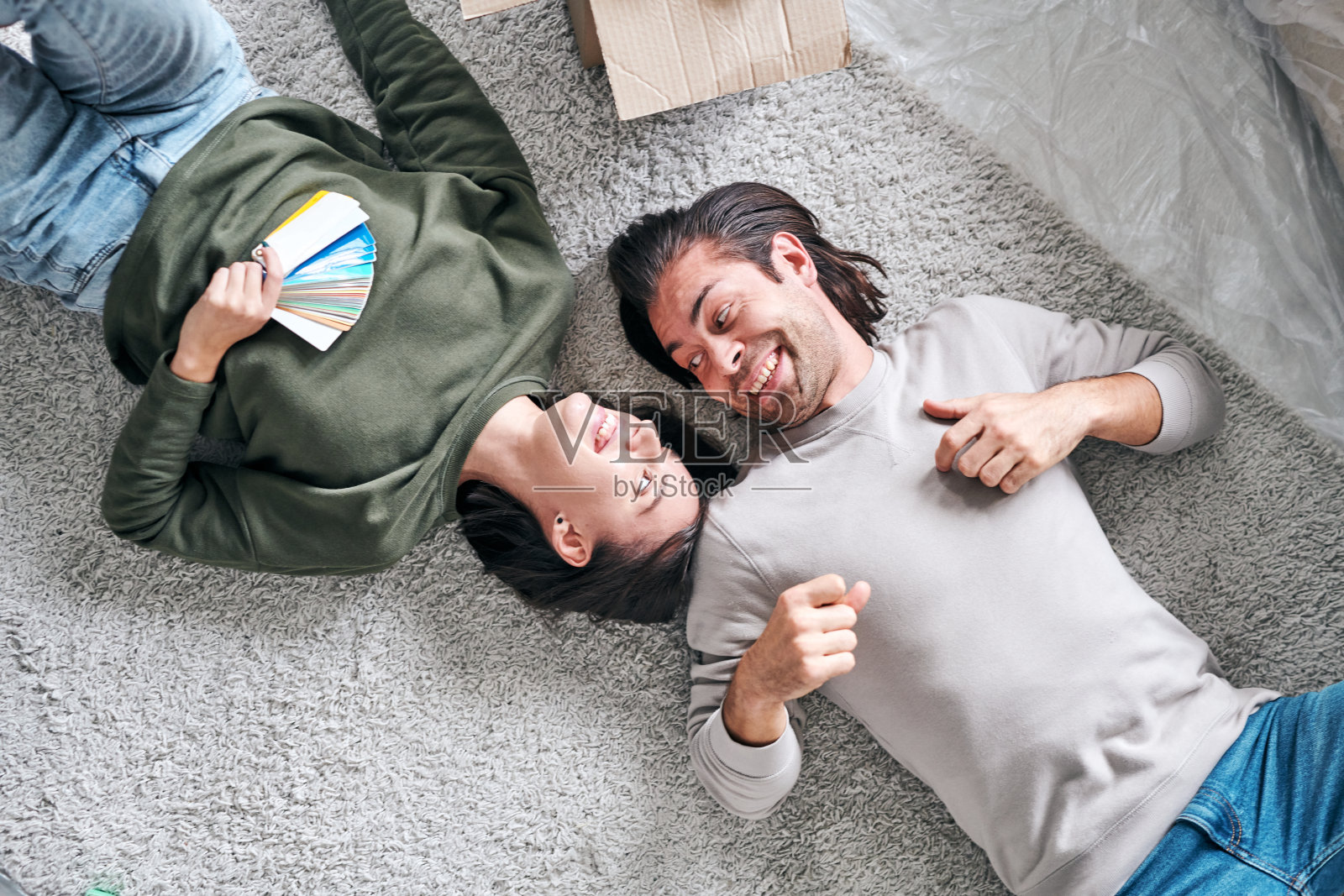 俯视图的幸福年轻多情夫妇躺在他们的新房子的地板上照片摄影图片