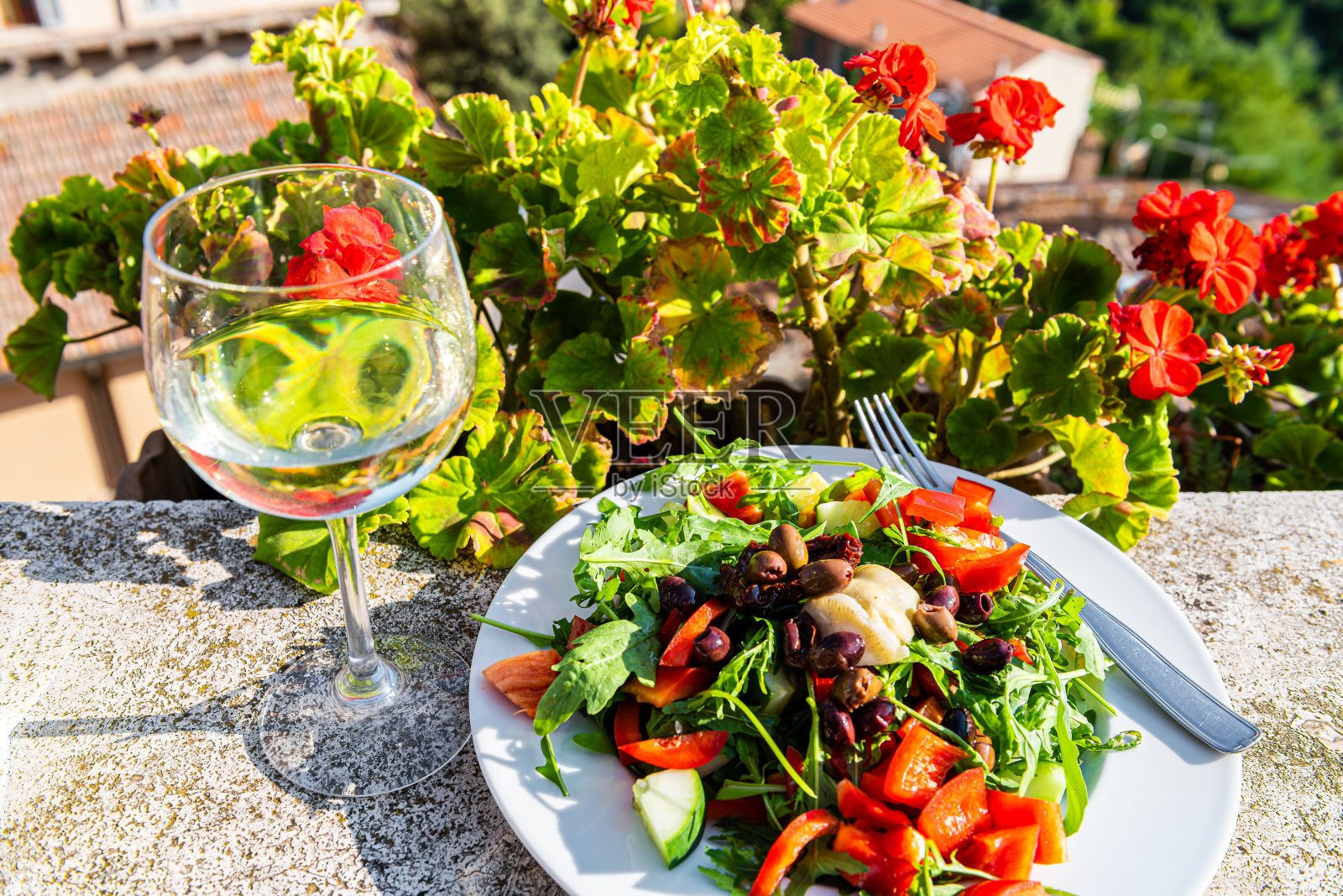 白色的葡萄酒杯和沙拉盘在花园与红色天竺葵在意大利托斯卡纳夏季花园外面的特写照片摄影图片