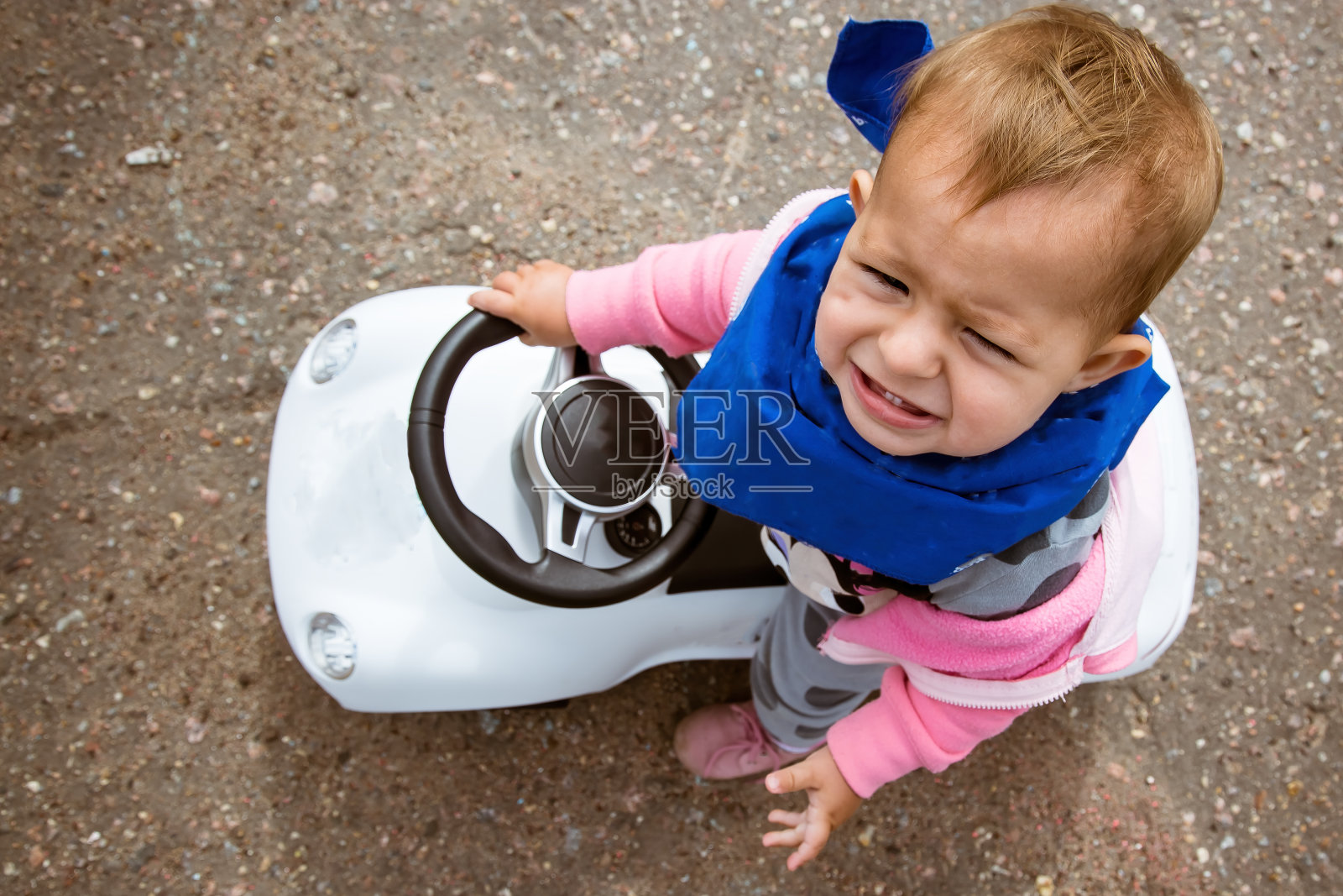 一个小孩正骑着一辆玩具车。而且非常不高兴。从以上观点。一辆需要踢的特殊车。Tolokar。照片摄影图片