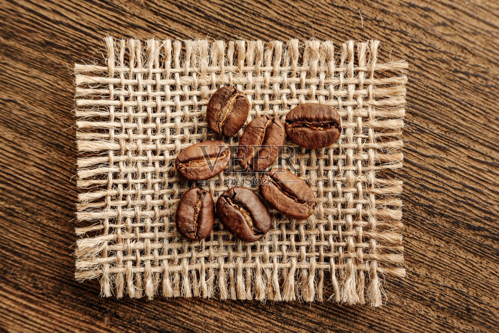 粗麻布上的咖啡豆在粗糙的木头背景上的特写。照片摄影图片