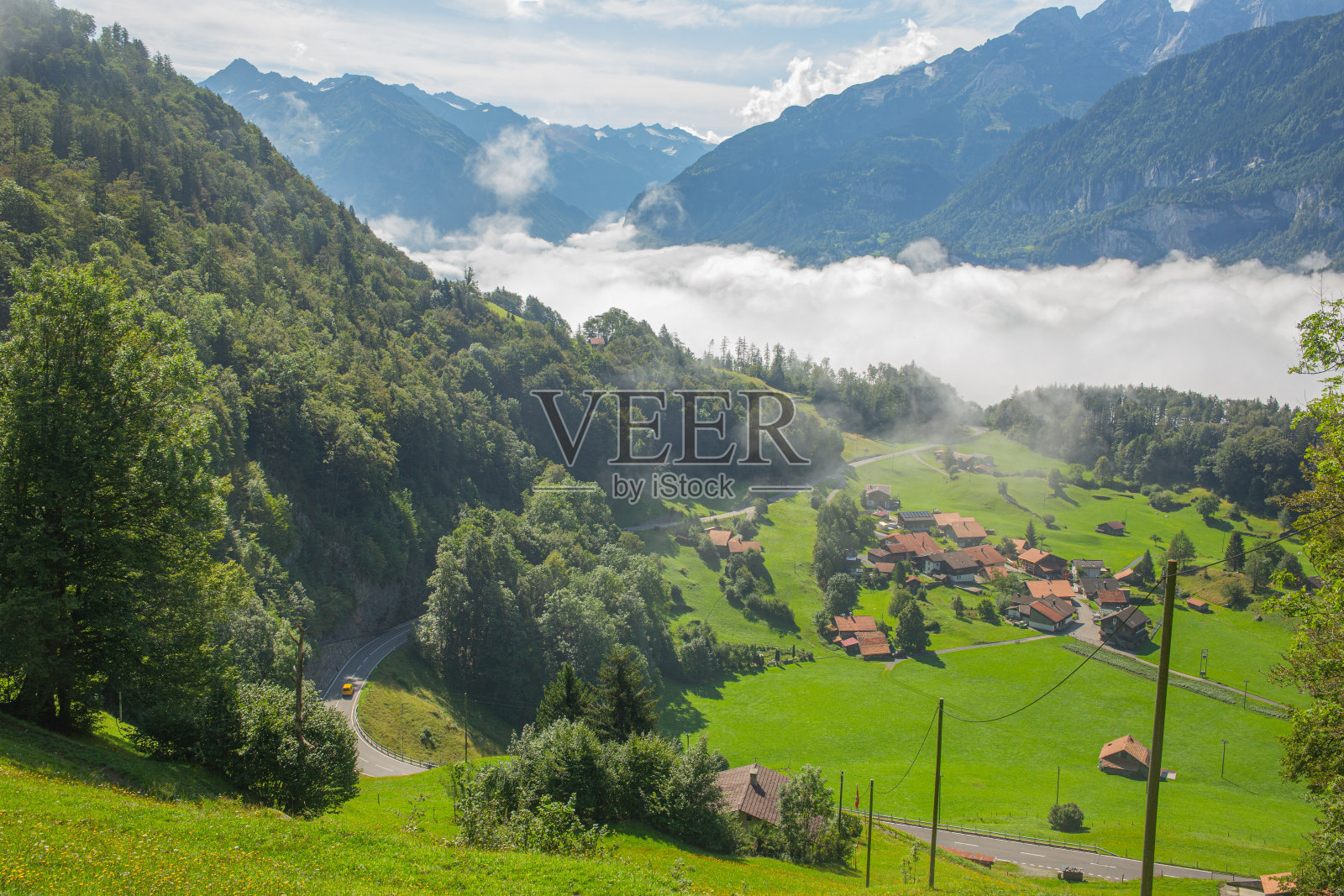风景优美的阿尔卑斯山，山坡沐浴着阳光，低云躺在山谷，瑞士照片摄影图片