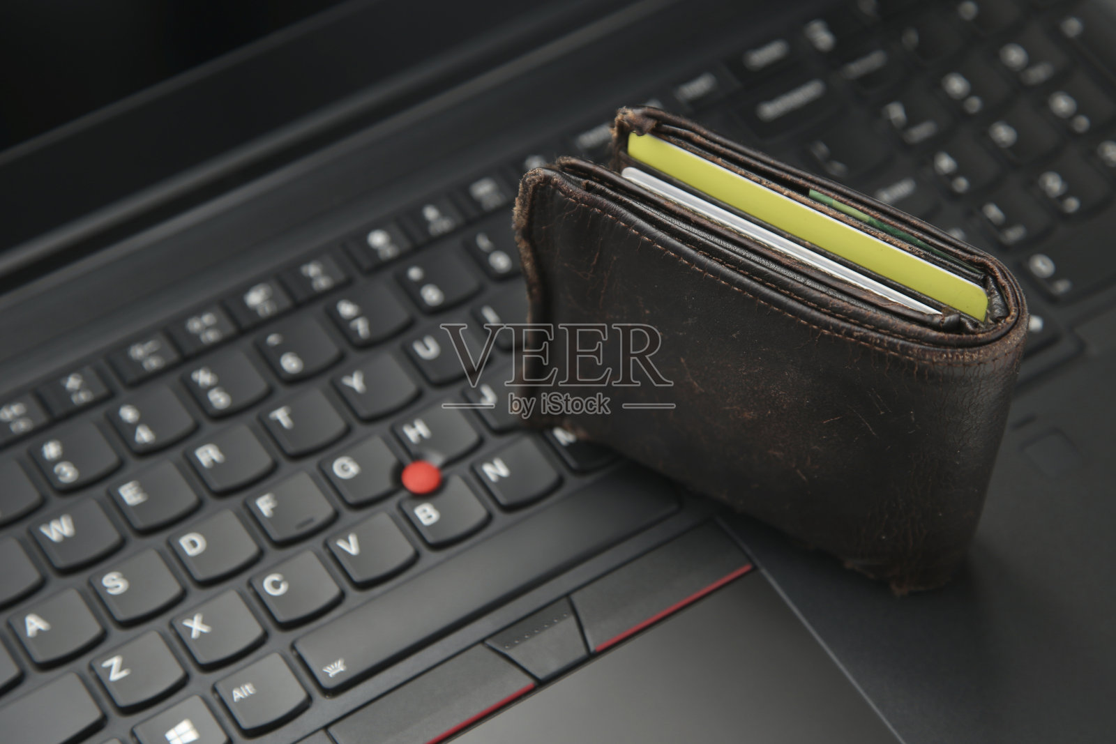 一个装满钱的钱包和一台笔记本电脑。网上购买产品的概念形象。照片摄影图片