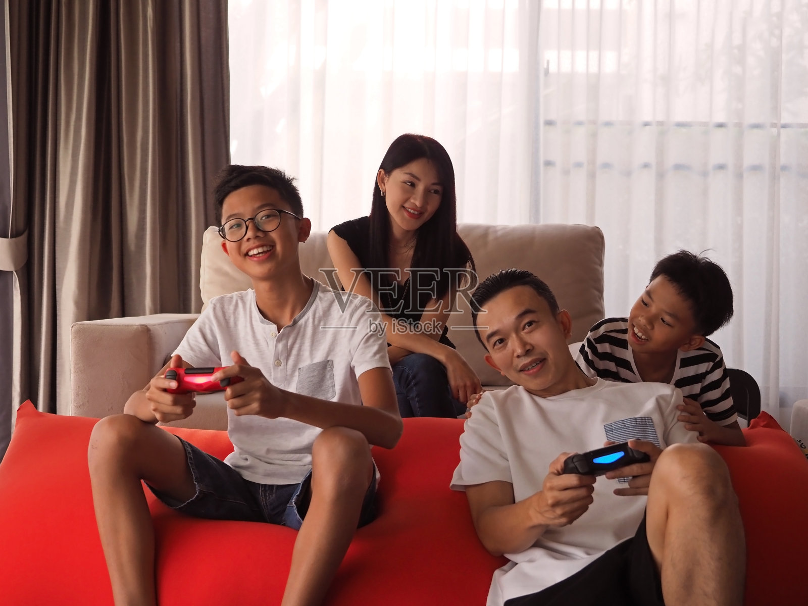 亚洲家庭坐在沙发上玩VDO游戏。照片摄影图片