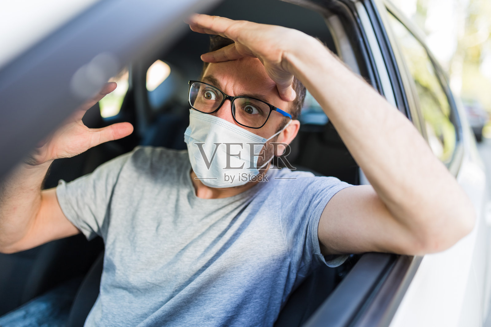 男性司机在车内承受压力时戴上防护面罩。照片摄影图片
