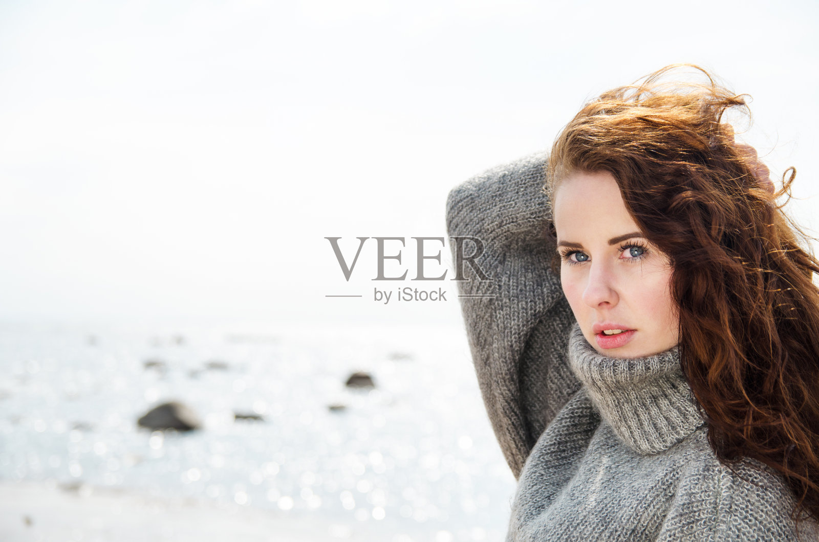有魅力的女人穿着暖和的羊毛衫在寒冷的海滩上照片摄影图片