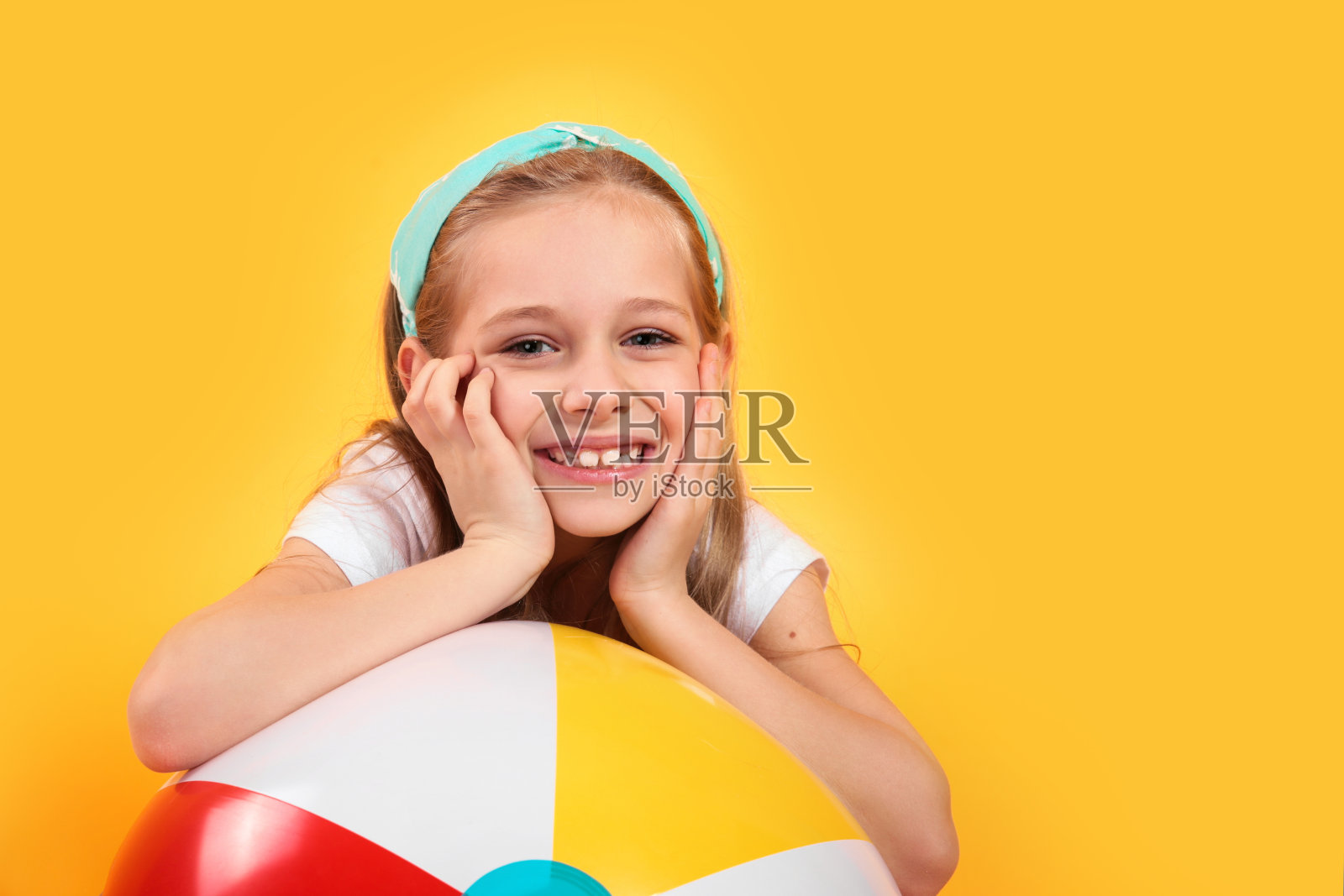 滑稽快乐的孩子的肖像在夏天的衣服与沙滩球在黄色的背景照片摄影图片