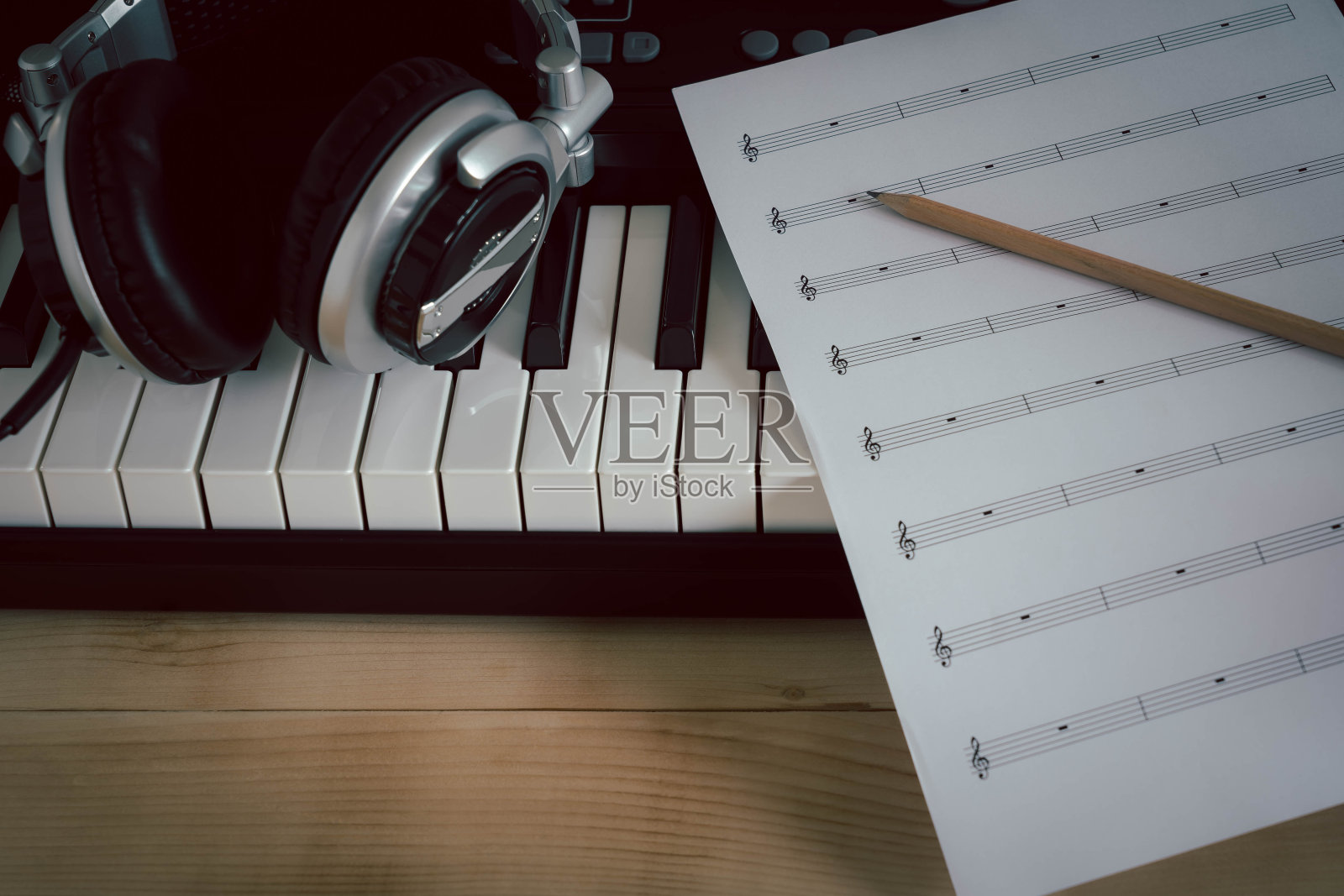 乐器概念背景。特写一组音乐工具，让音乐家用铅笔在纸上笔记和电子键盘，耳机在棕色的木头上创作歌曲。副本的空间。照片摄影图片