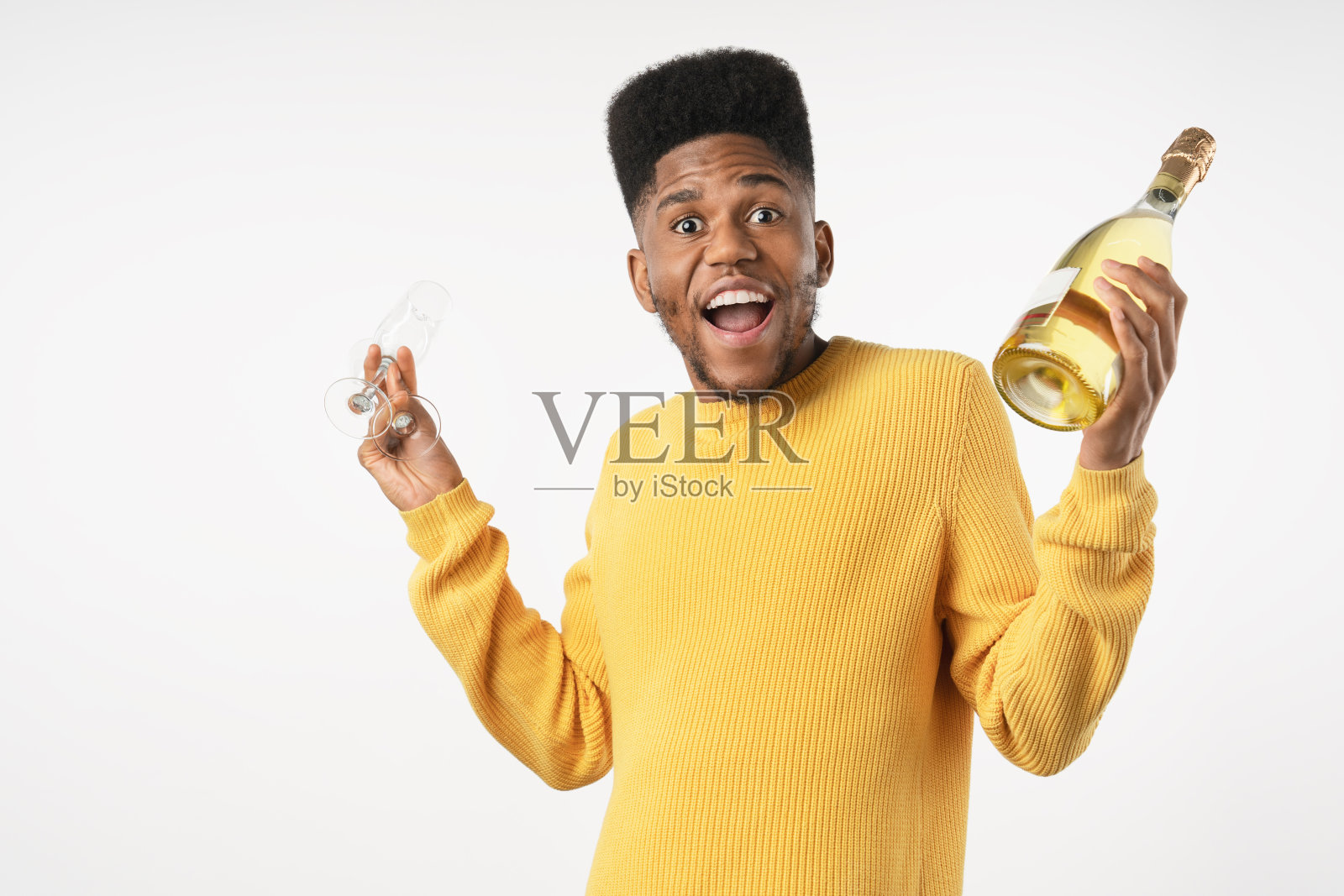 一名年轻的非洲男子用酒瓶和酒杯在白色的背景下庆祝照片摄影图片