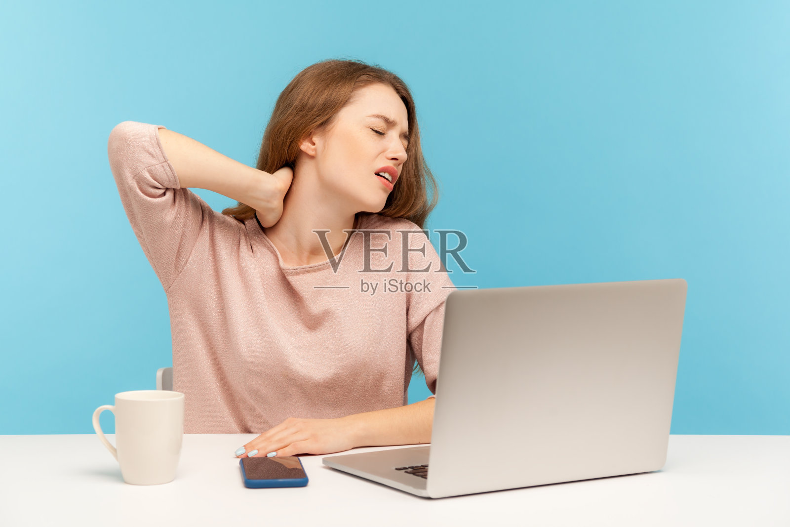 一名生病的年轻女员工坐在工作场所使用笔记本电脑，颈部、肩膀和背部疼痛，感到不舒服照片摄影图片