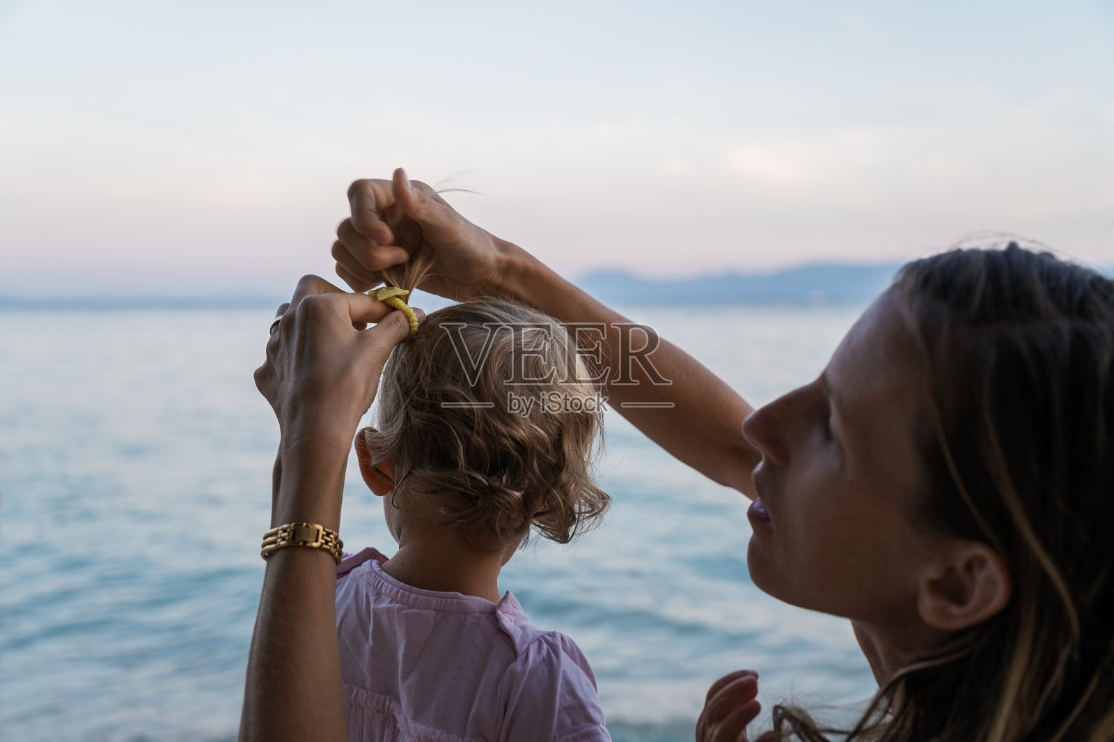 母亲在海边为女儿梳头照片摄影图片