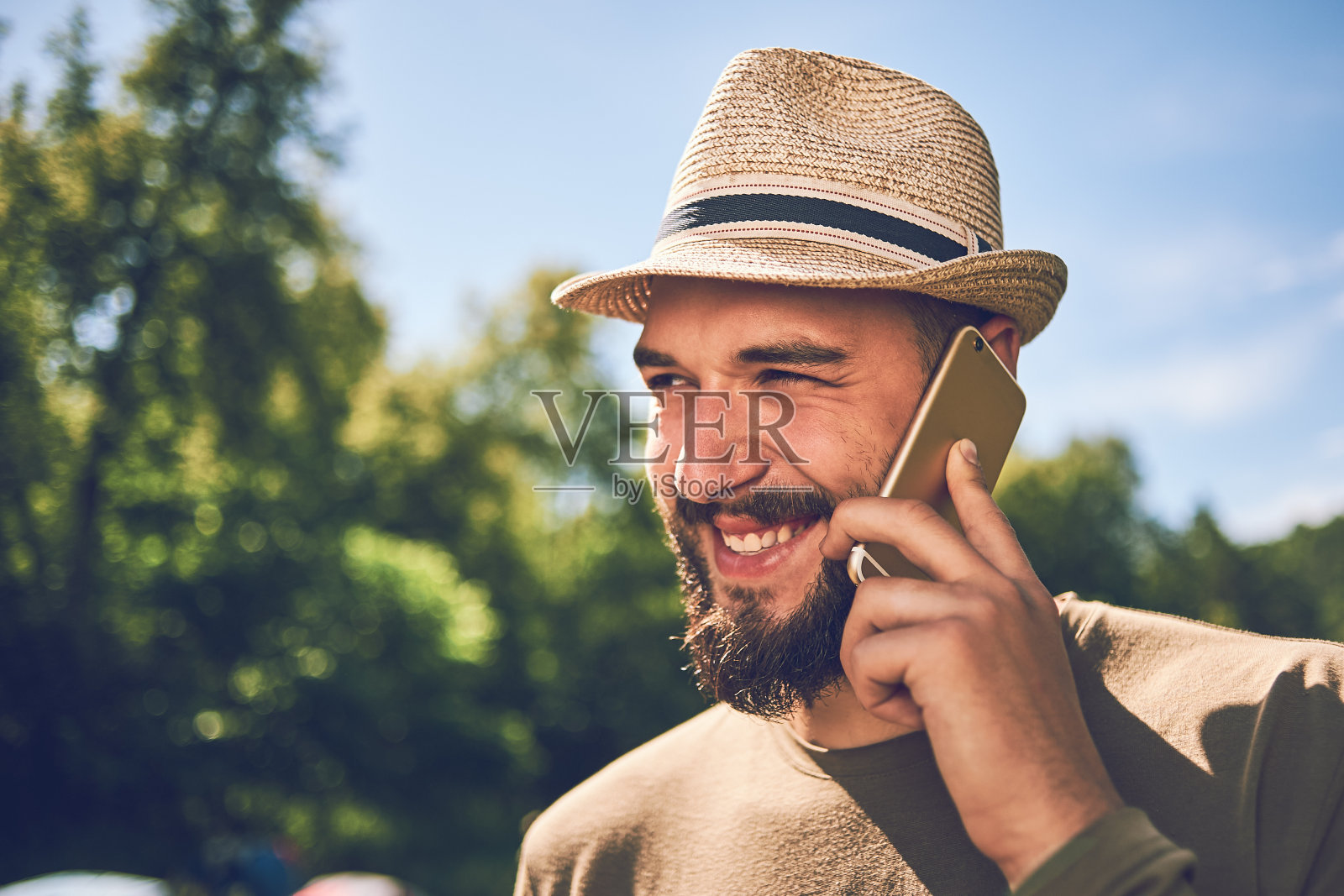 在自然背景下拿着智能手机的大胡子年轻男子照片摄影图片