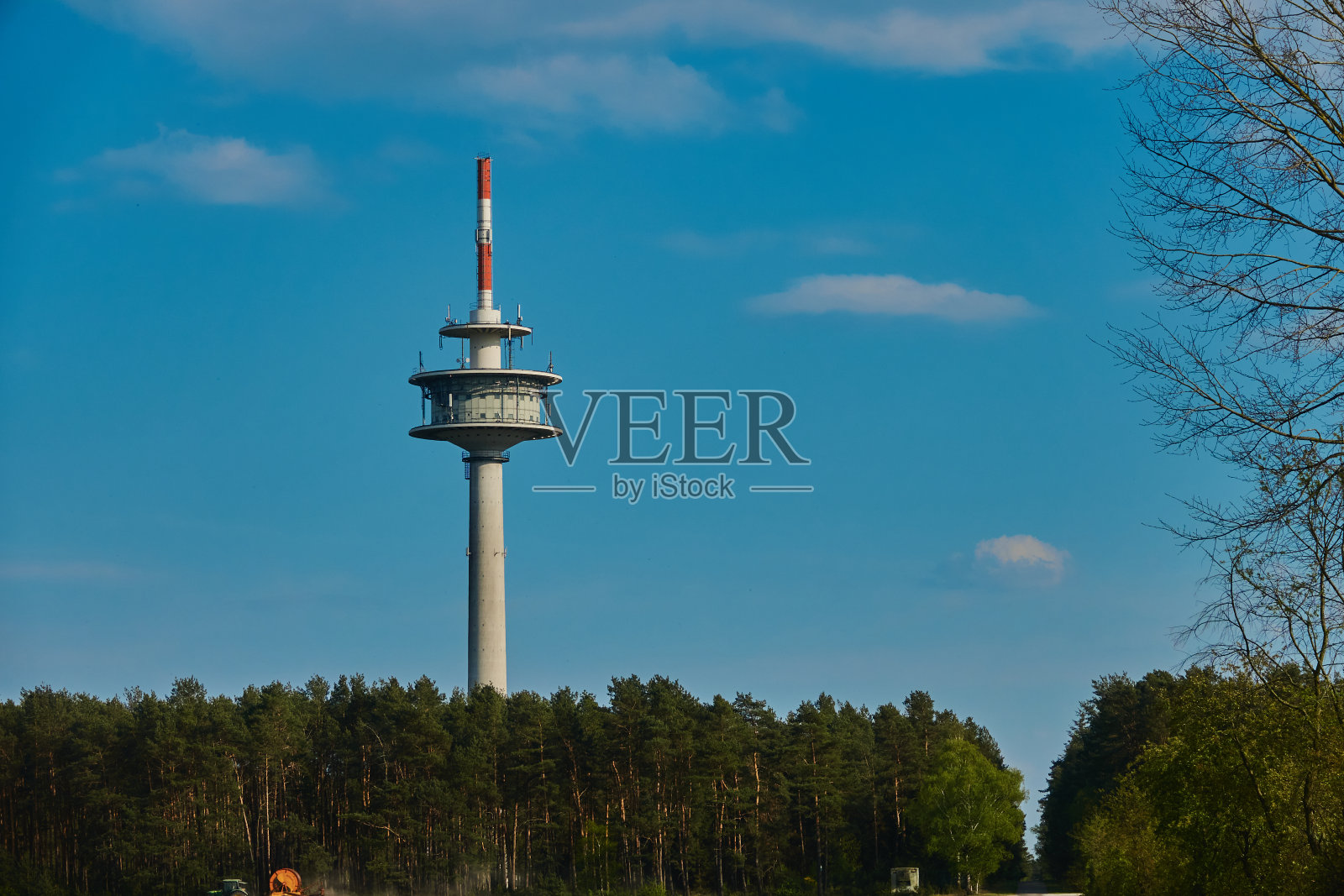 高高的电视塔后面是一片森林，前面是一片蓝天照片摄影图片