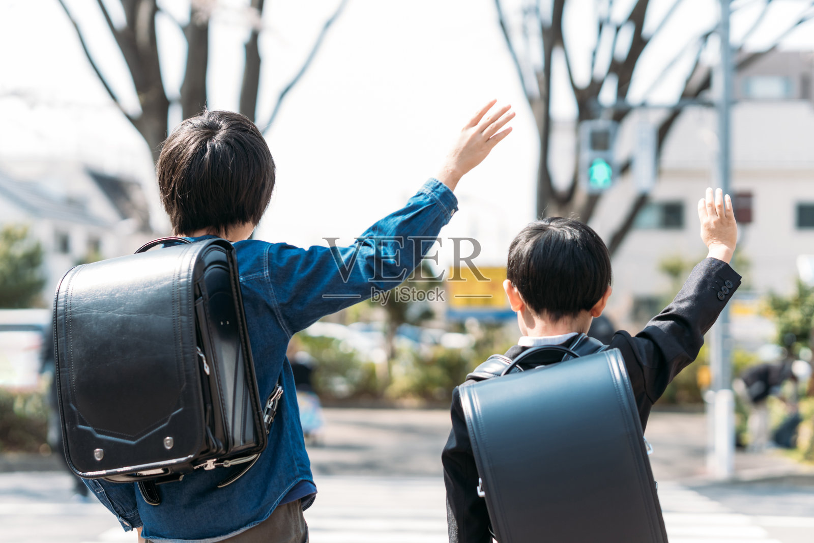 日本小学高年级学生和一年级学生在十字路口举手照片摄影图片