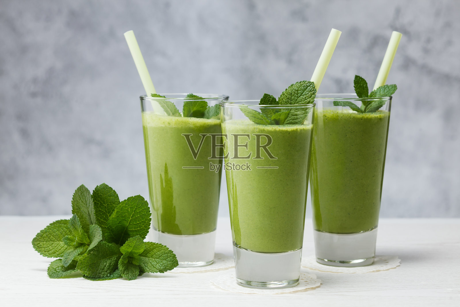 玻璃杯中新鲜混合的绿色水果冰沙。照片摄影图片